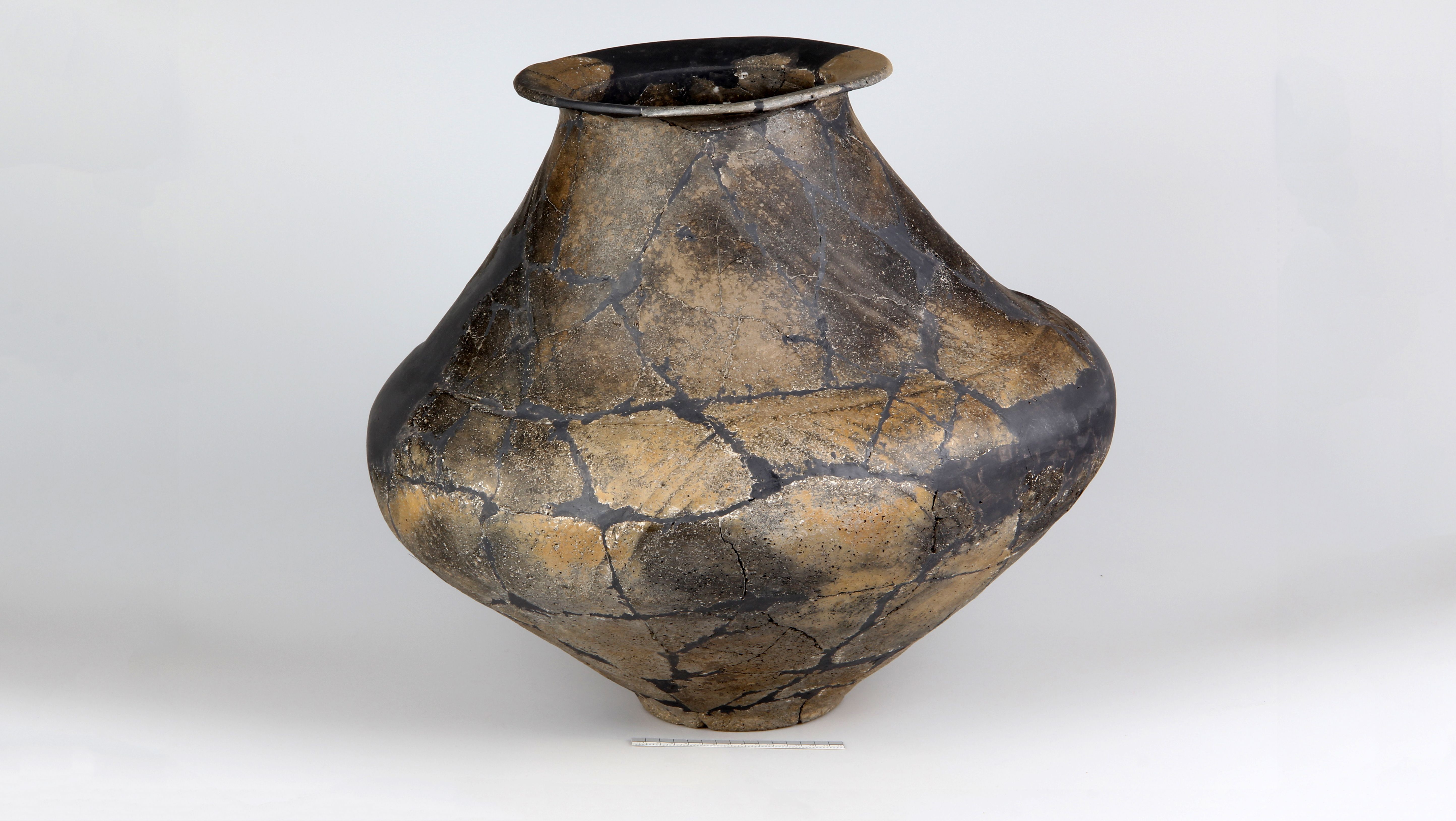 Antique ceramic vase with repaired cracks on a white background.