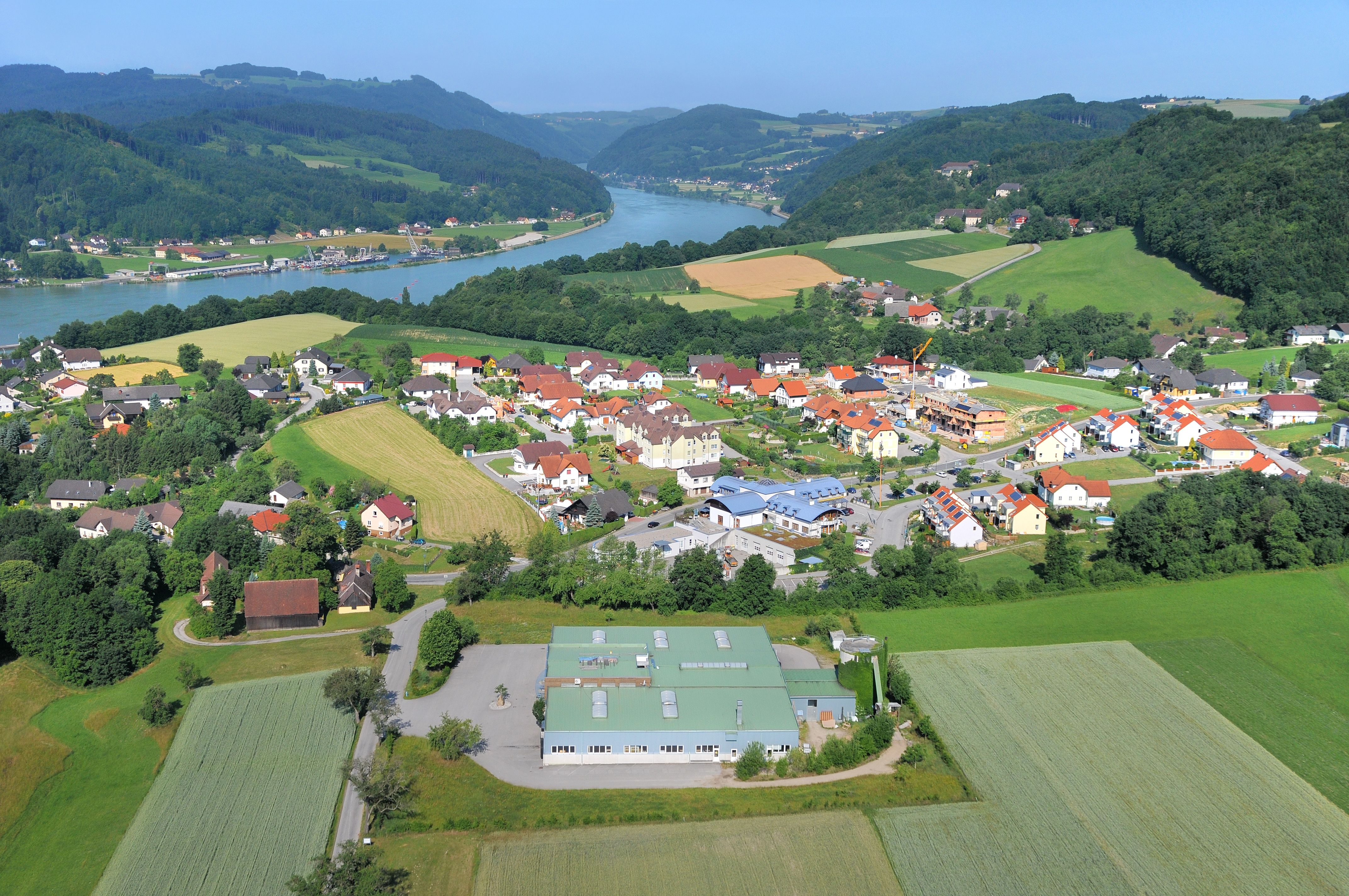 Aerial view of a village in the Danube valley with river and hills in the background.