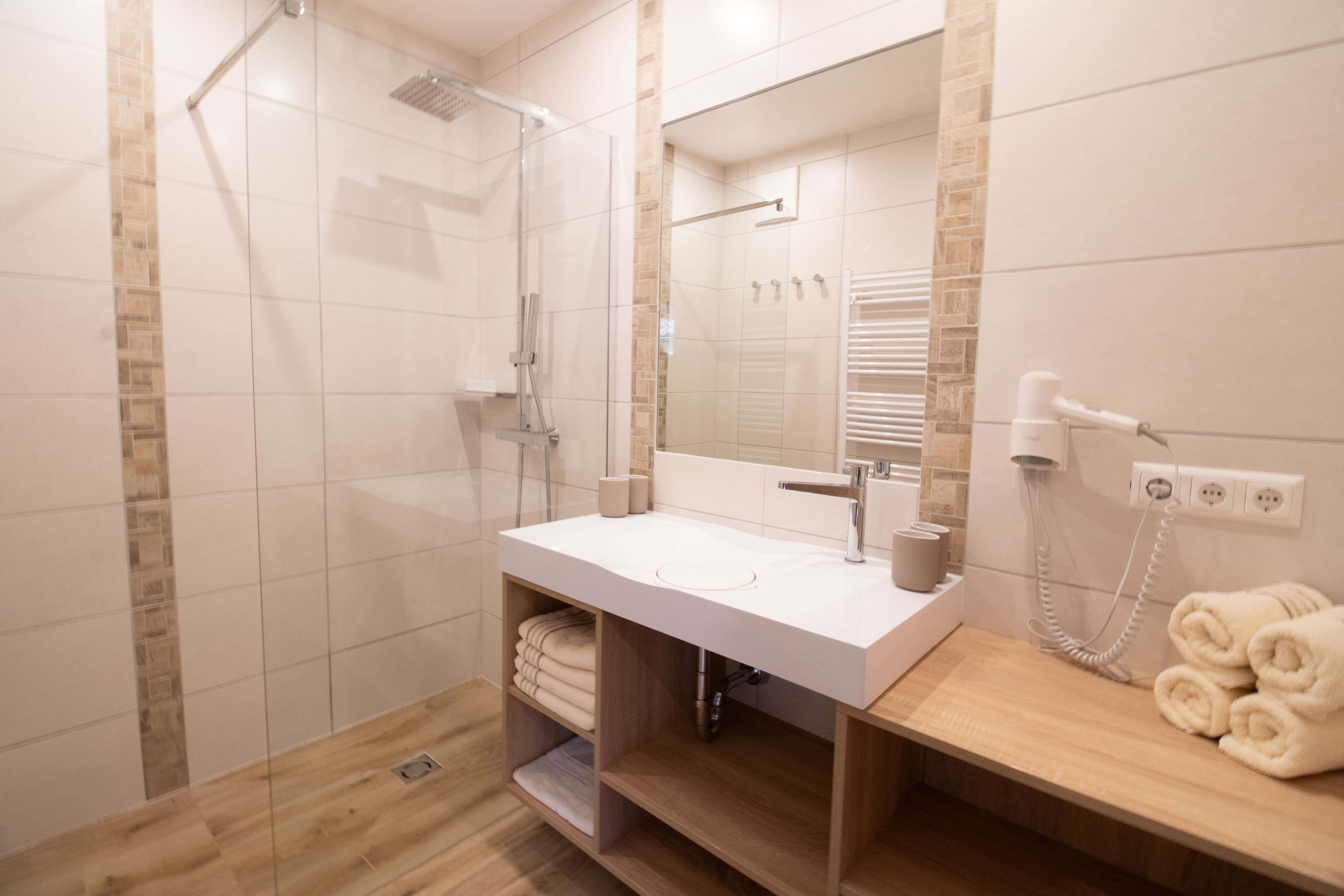 Modern bathroom with a shower, sink, and towels.