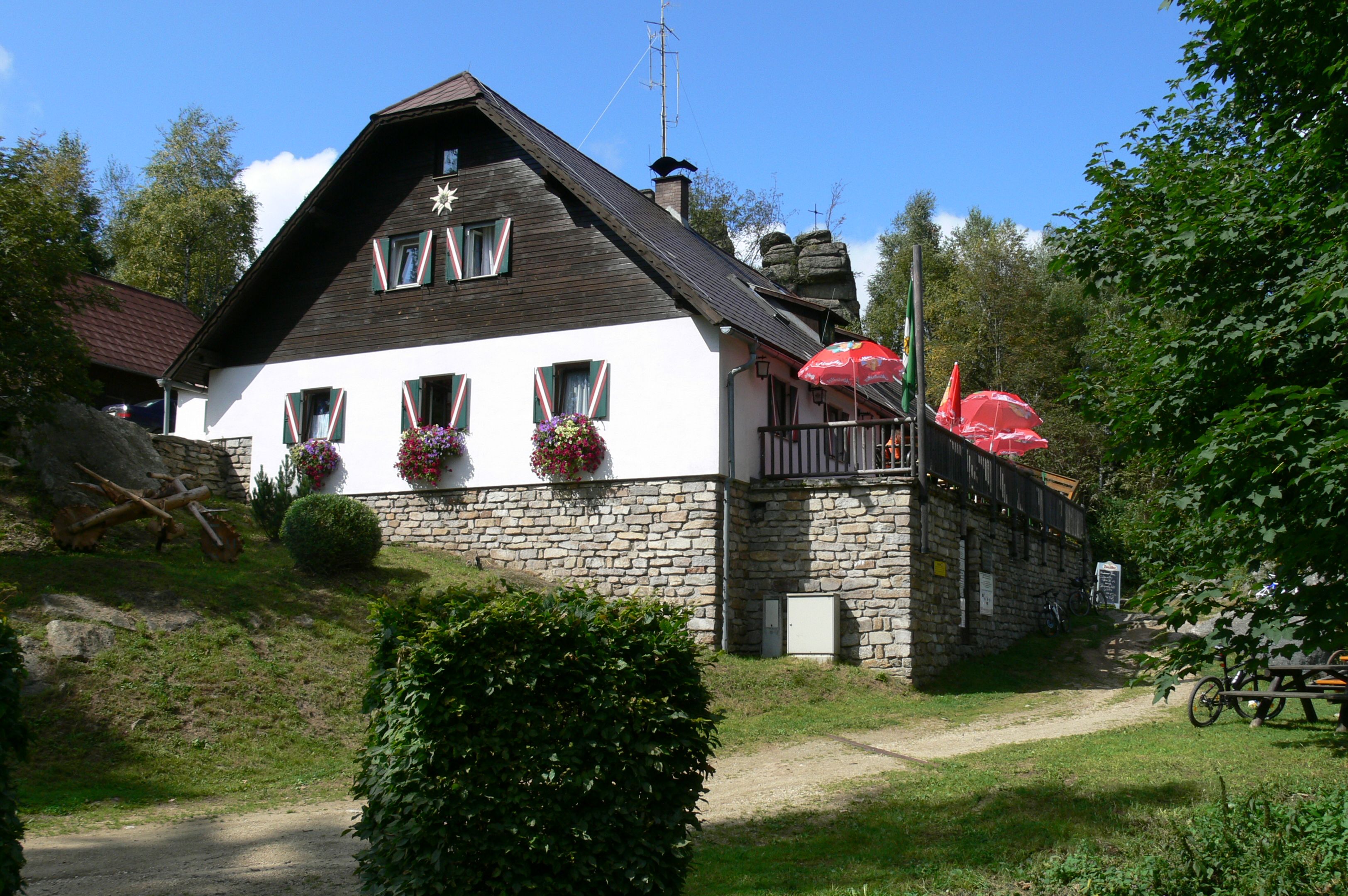 A mountain hut with flowers and parasols on a terrace.