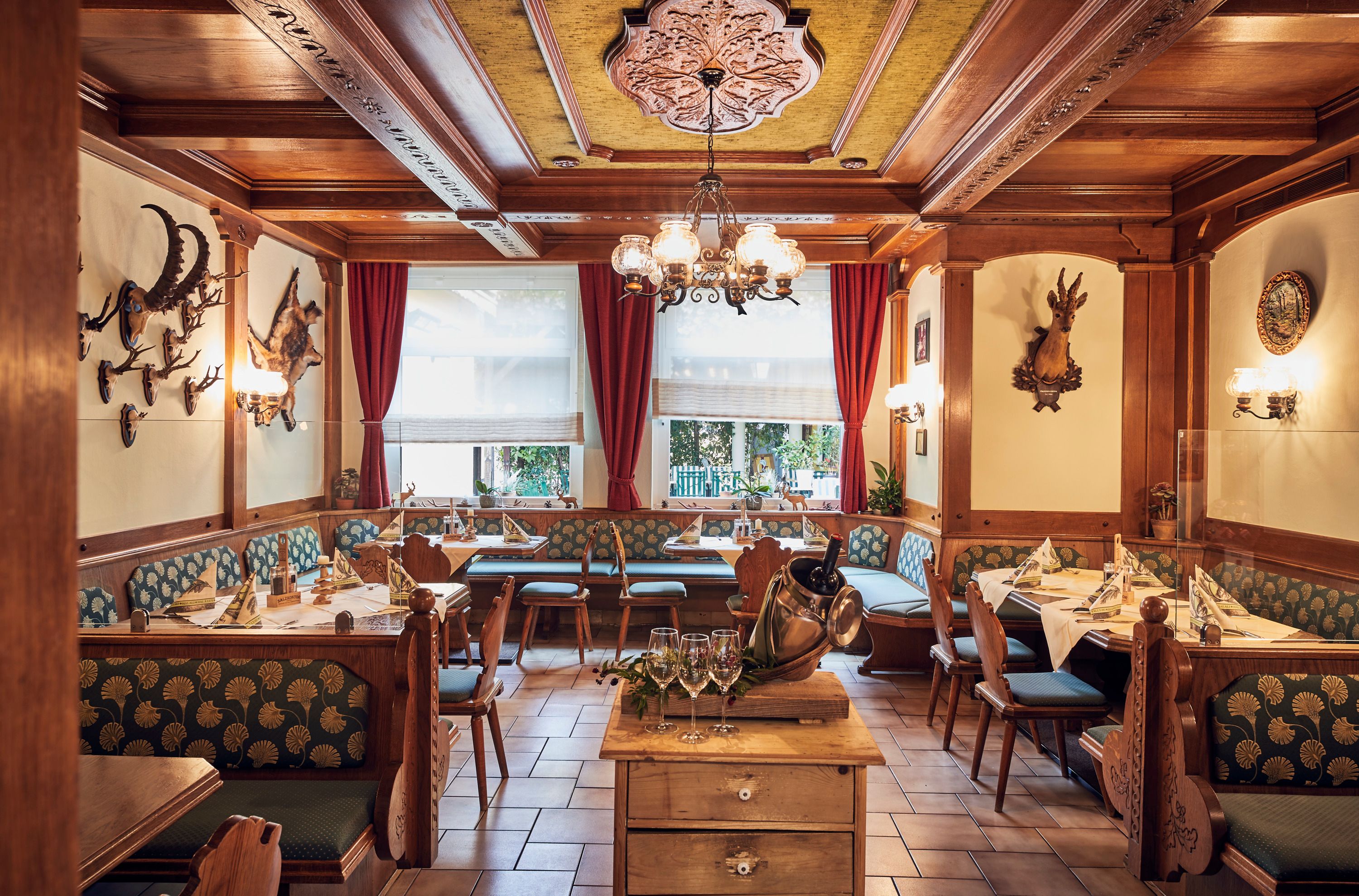 Cozy hunting parlor with wooden furniture, hunting trophies on the walls and laid tables.