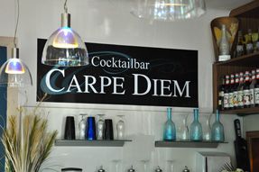 Interior view of a bar with a sign 'Cocktailbar Carpe Diem' on the wall.