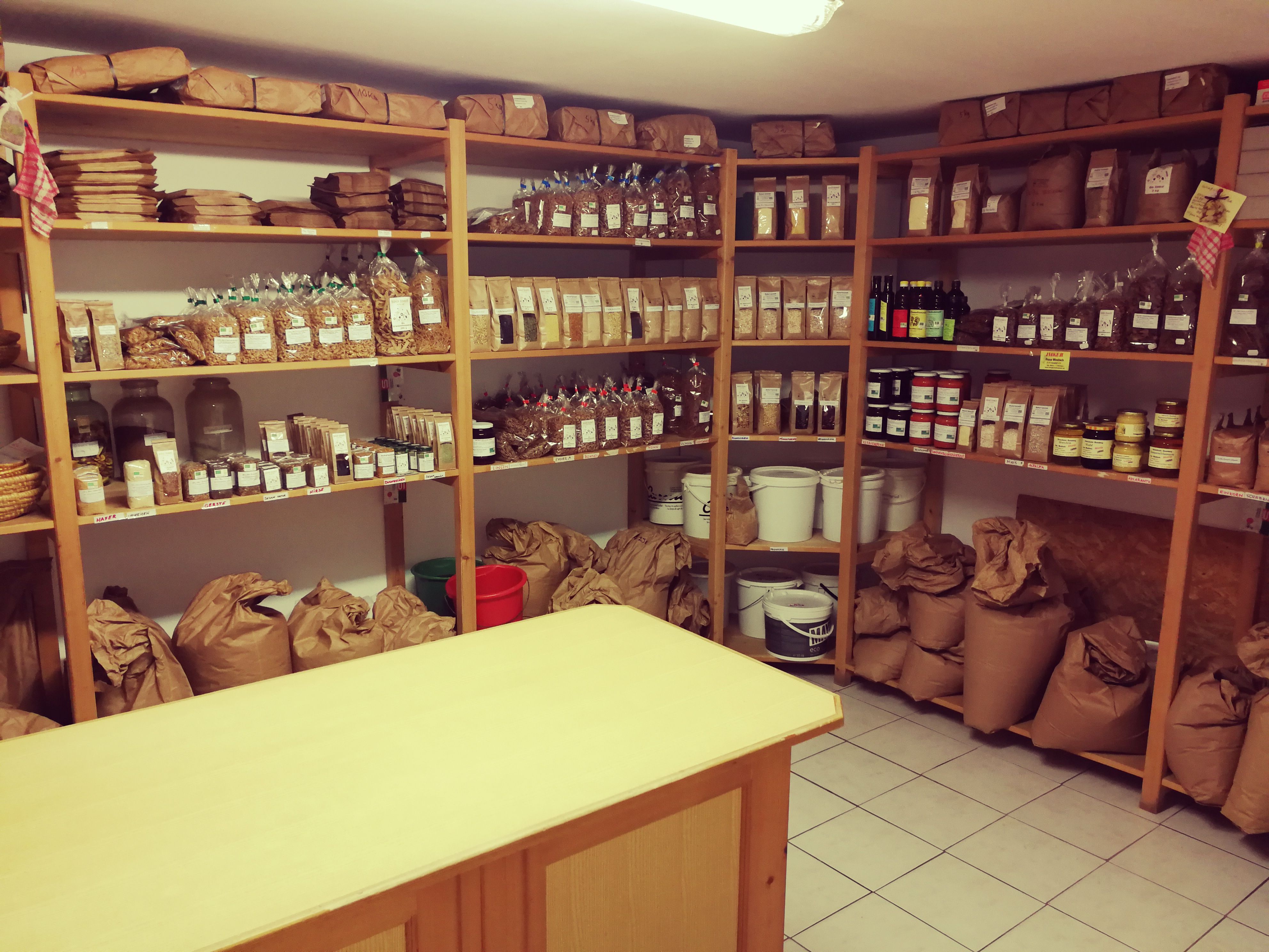 A storeroom with shelves full of food in paper bags and jars.