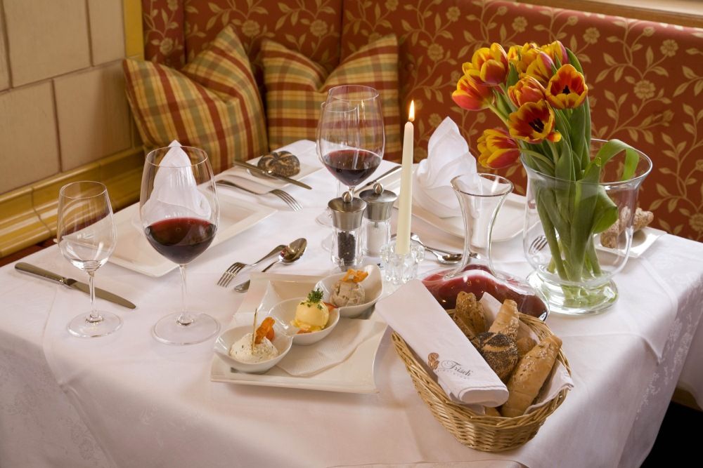 An elegantly laid table with wine glasses, candles, tulips and bread.