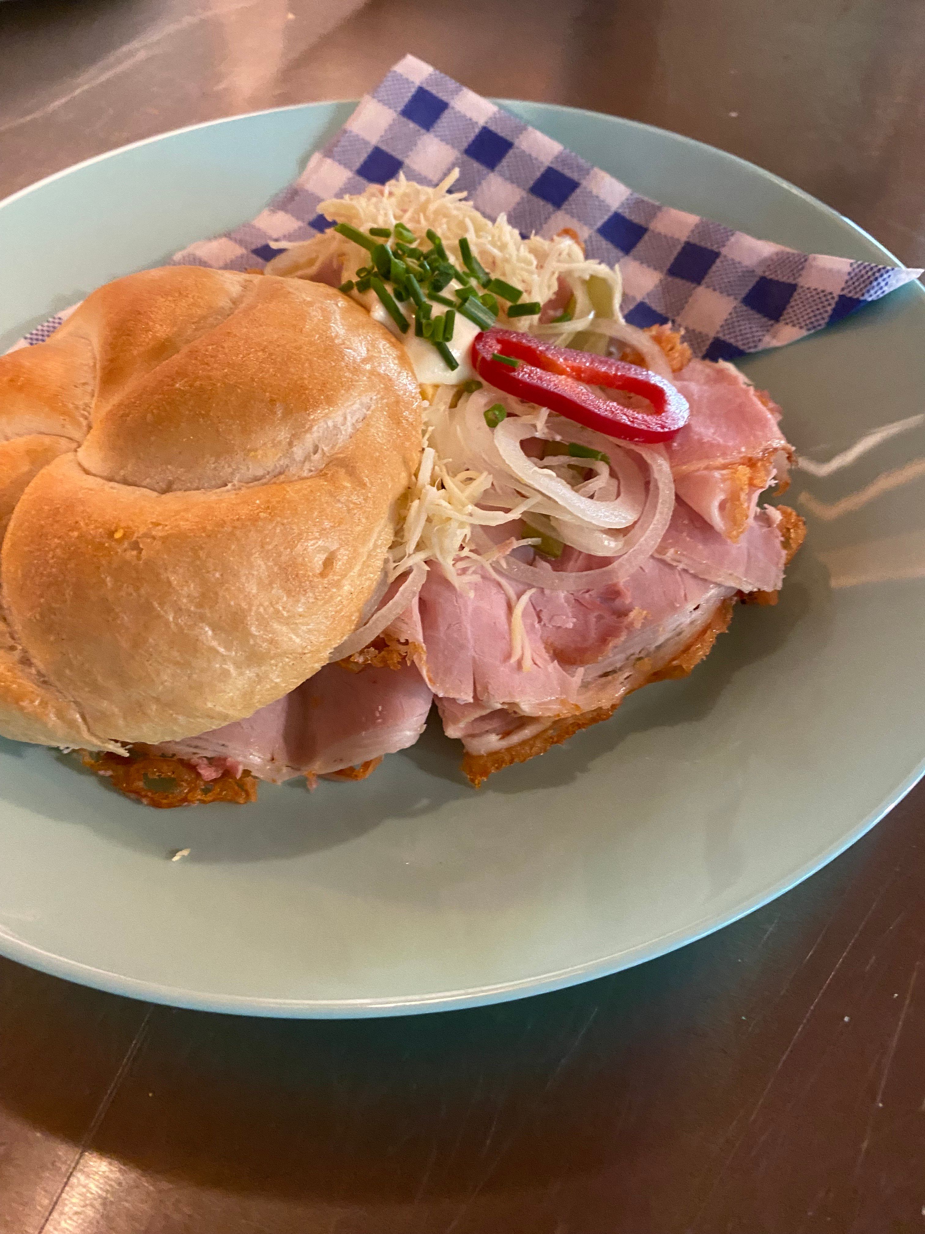 A sandwich with ham, onions and peppers on a plate.