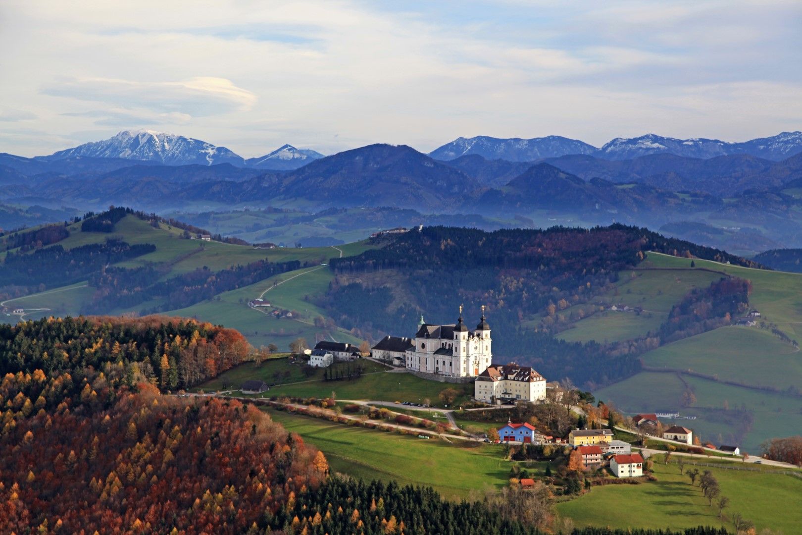 Panoramic view over the Mostviertel with the Sonntagberg basilica in the foreground and mountains in the background.
