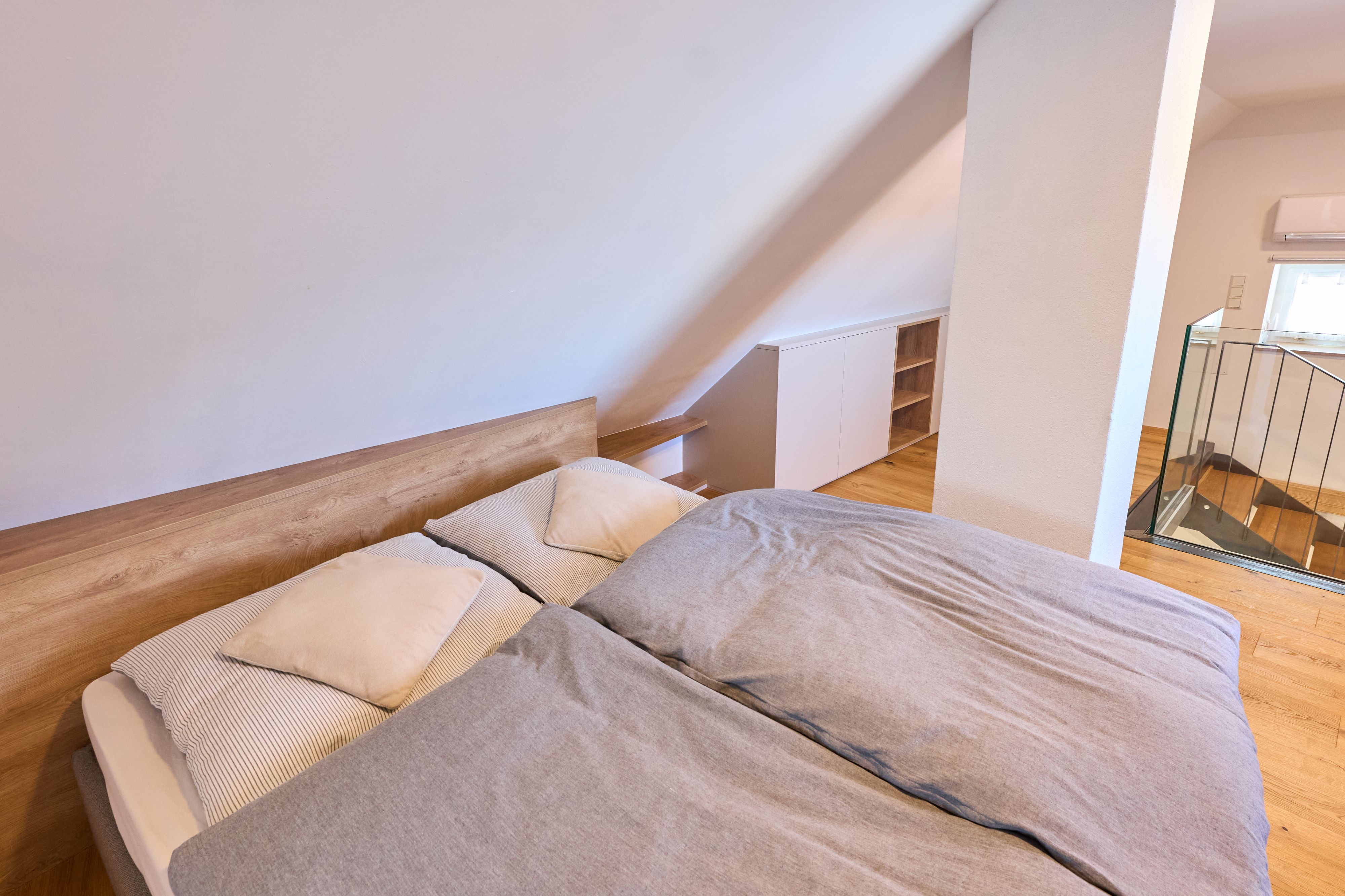 Attic bedroom with double bed and wooden floor.