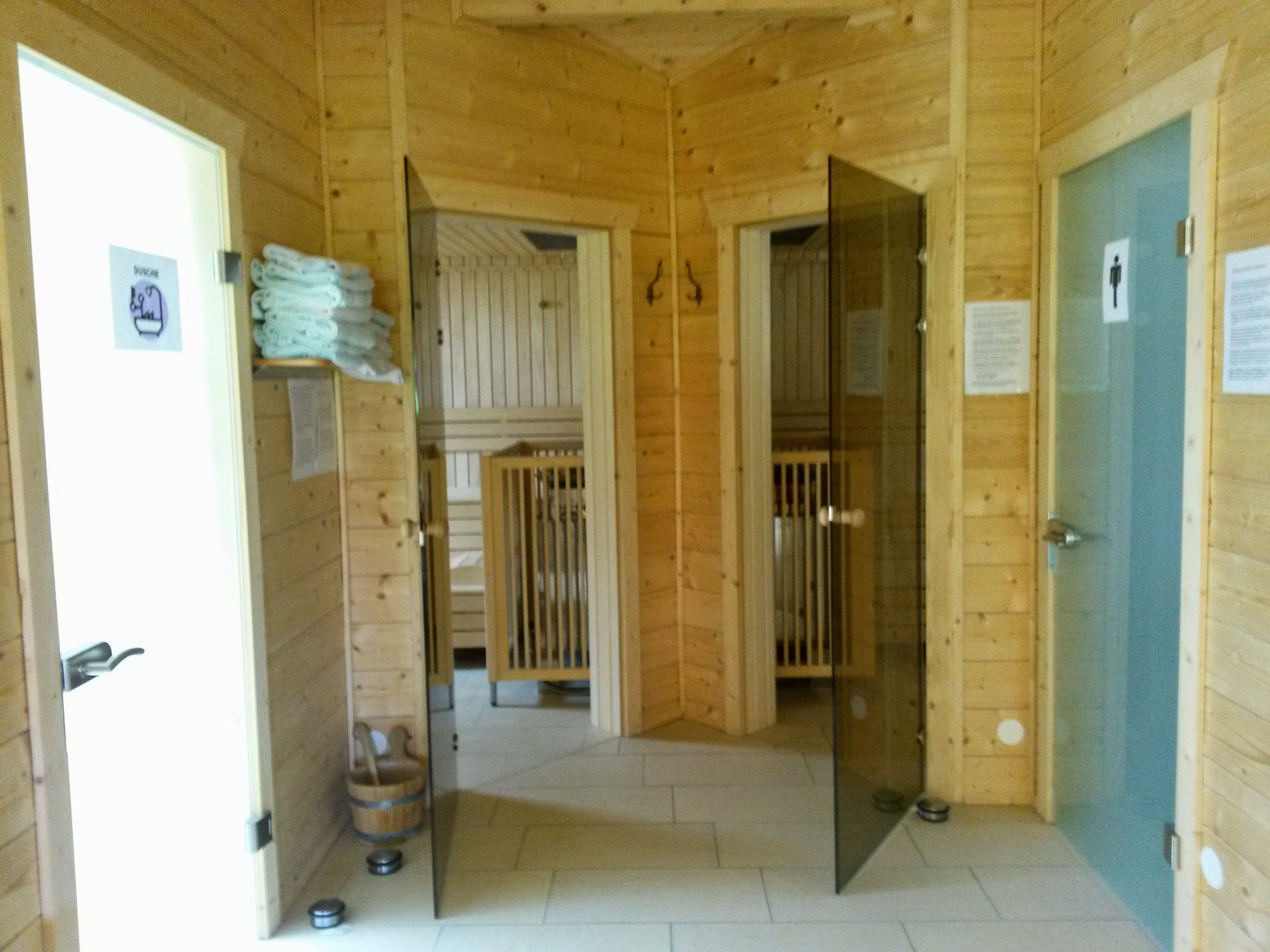 Interior view of a sauna with wooden walls, glass doors and towels.