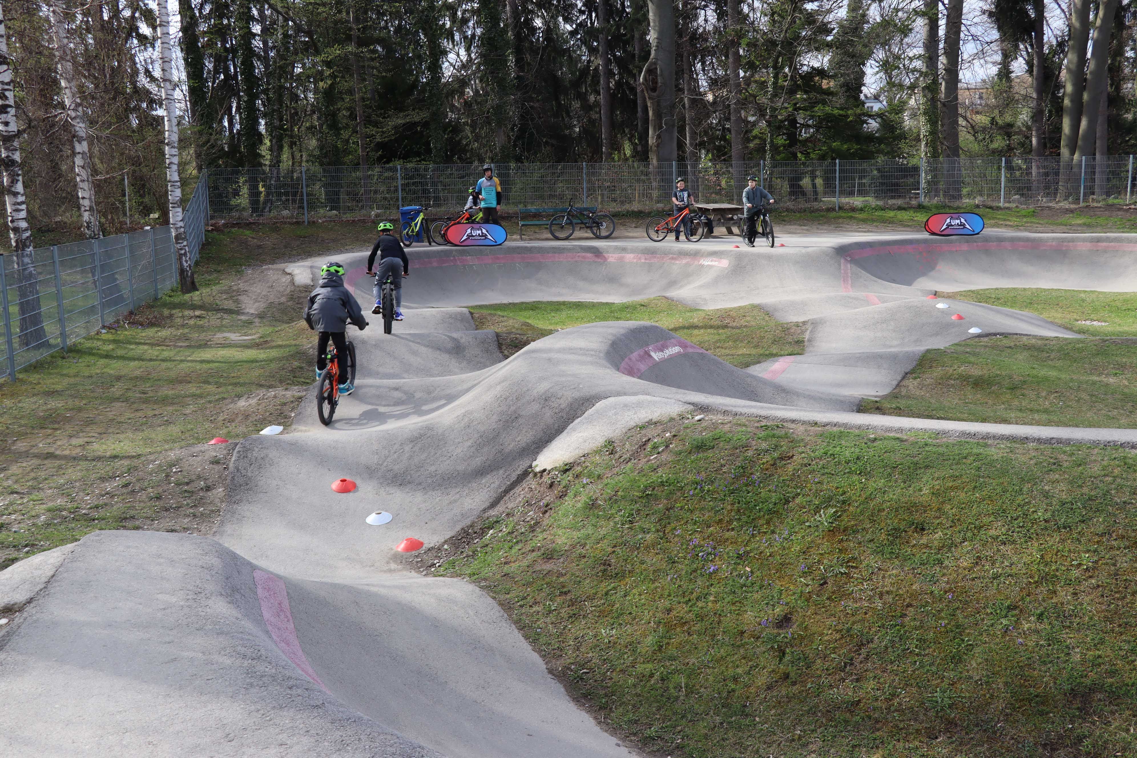 Children ride bikes on a pump track.