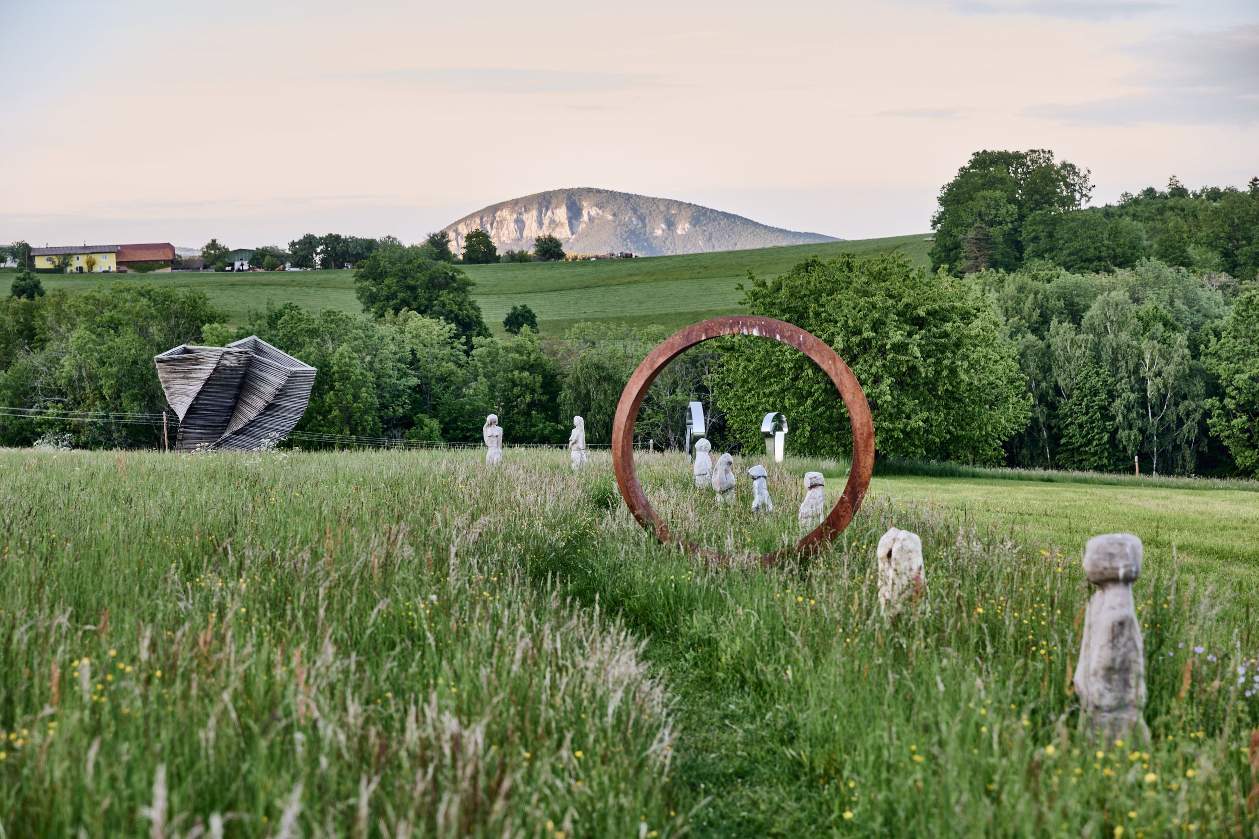Sculpture park with works of art and mountain in the background.