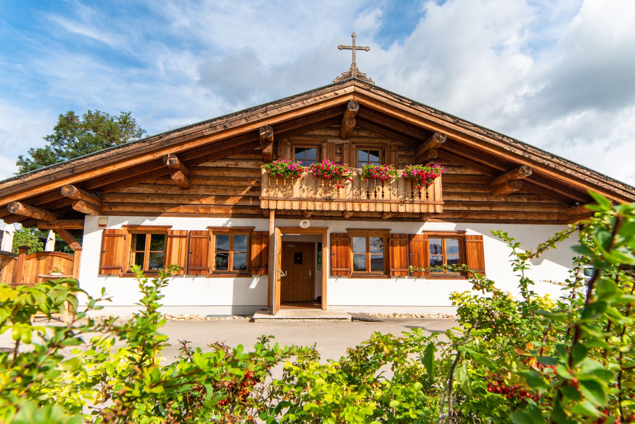 Traditional wooden house with balcony and flower boxes, blue sky in the background.