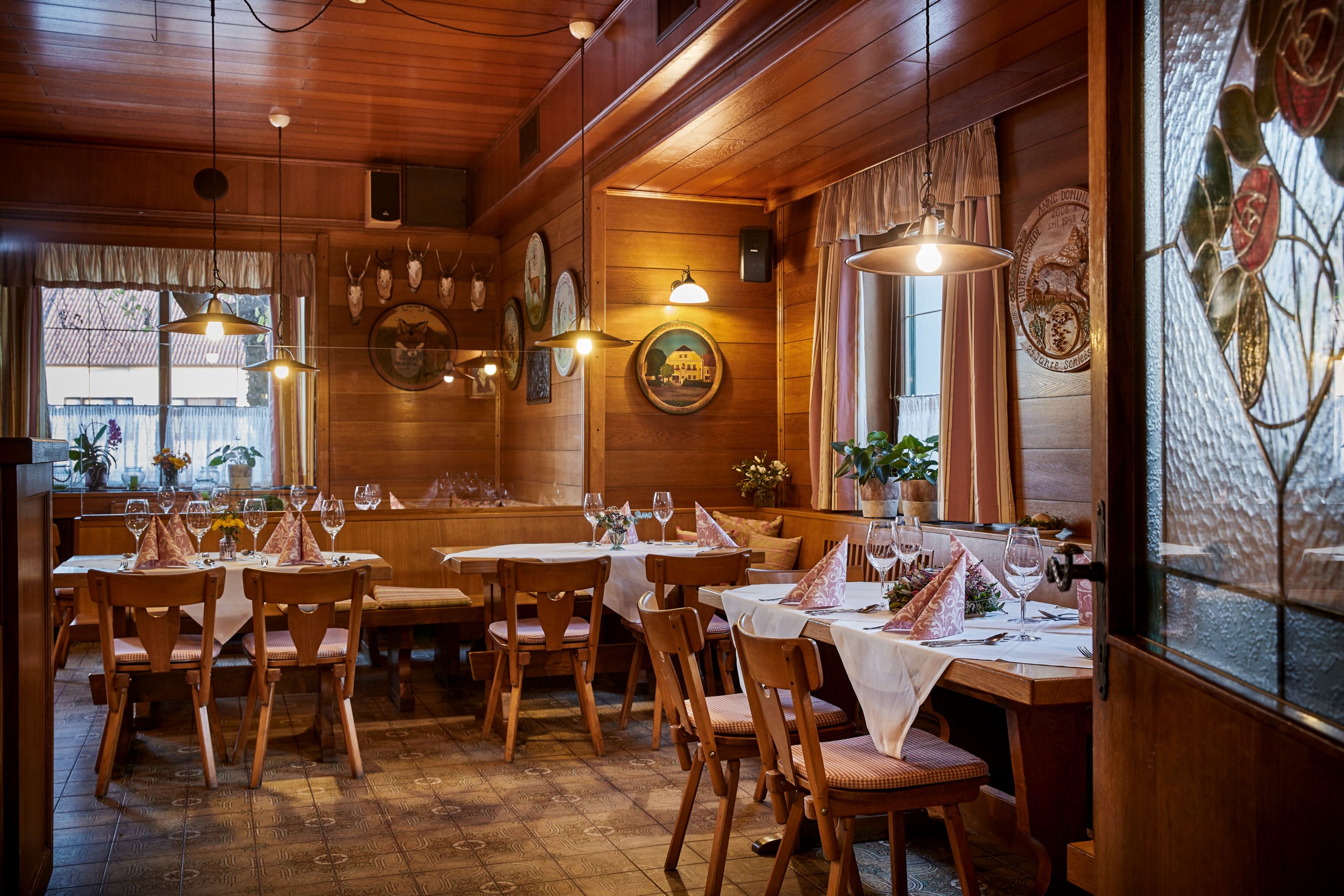 Cozy, wood-paneled tavern with set tables, chairs and decorative elements on the walls.