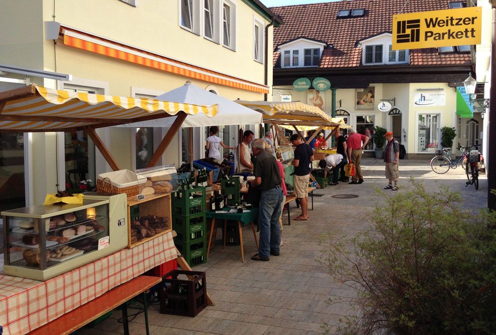 Farmers' market in a passageway with stalls and visitors.