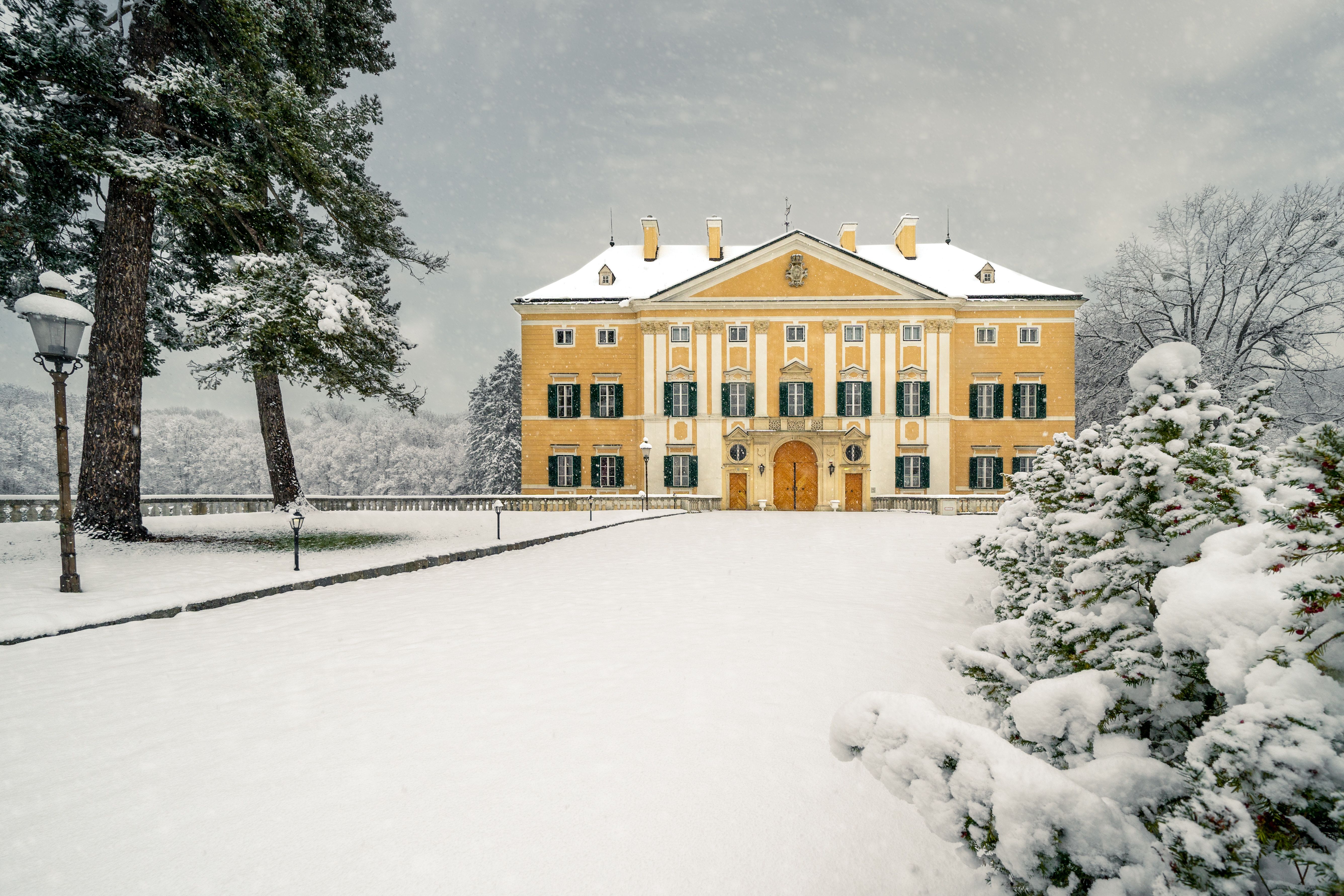 Frohsdorf Castle with its many windows and yellow façade covered in snow in winter.