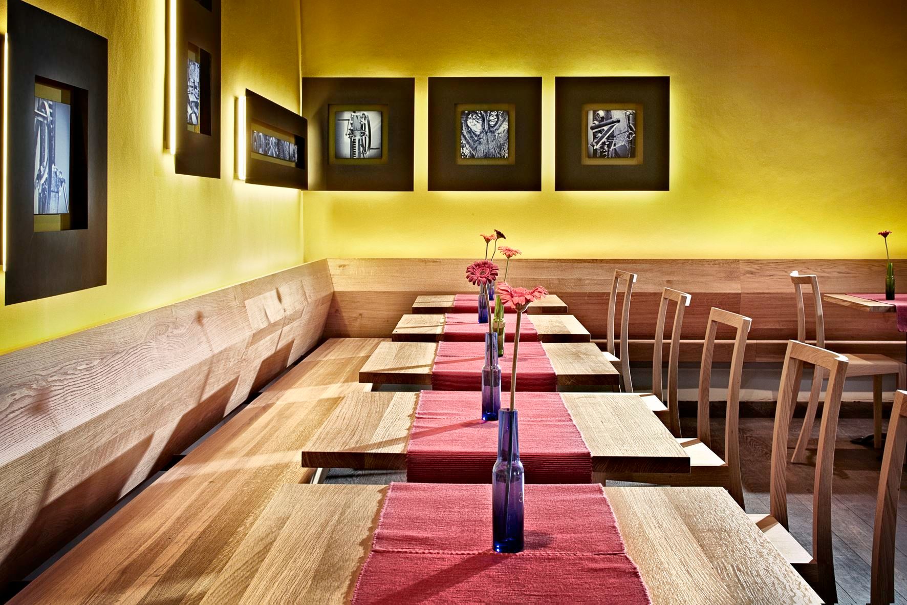 Interior view of a modern restaurant with wooden furniture and yellow walls.
