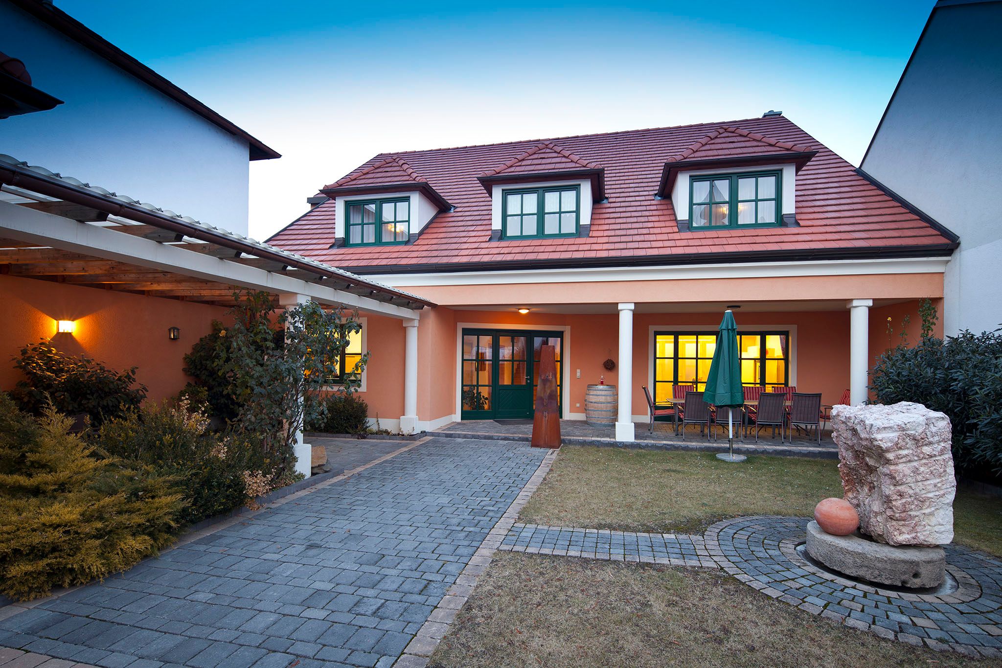 Guest house with red roof and garden in the foreground.