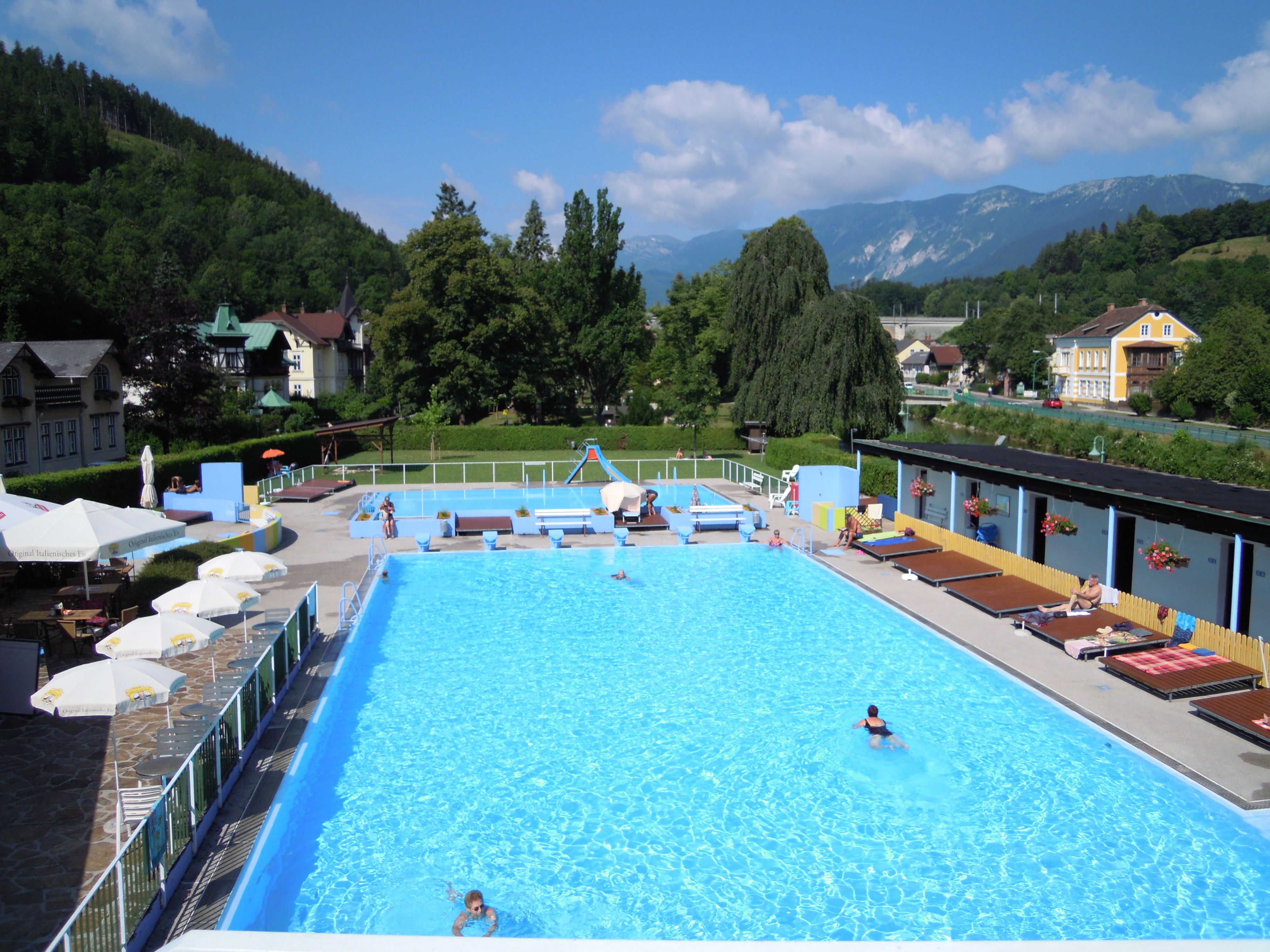 Payerbach outdoor pool with swimmers and surrounding landscape.
