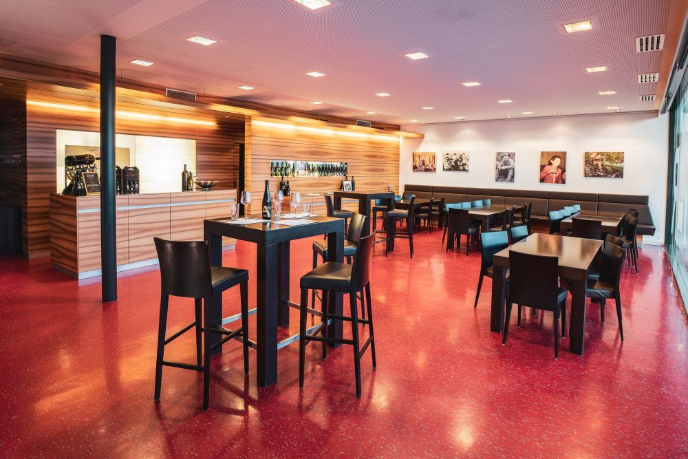 Modern tasting room with wooden counters, red floor tiles and black tables and chairs.