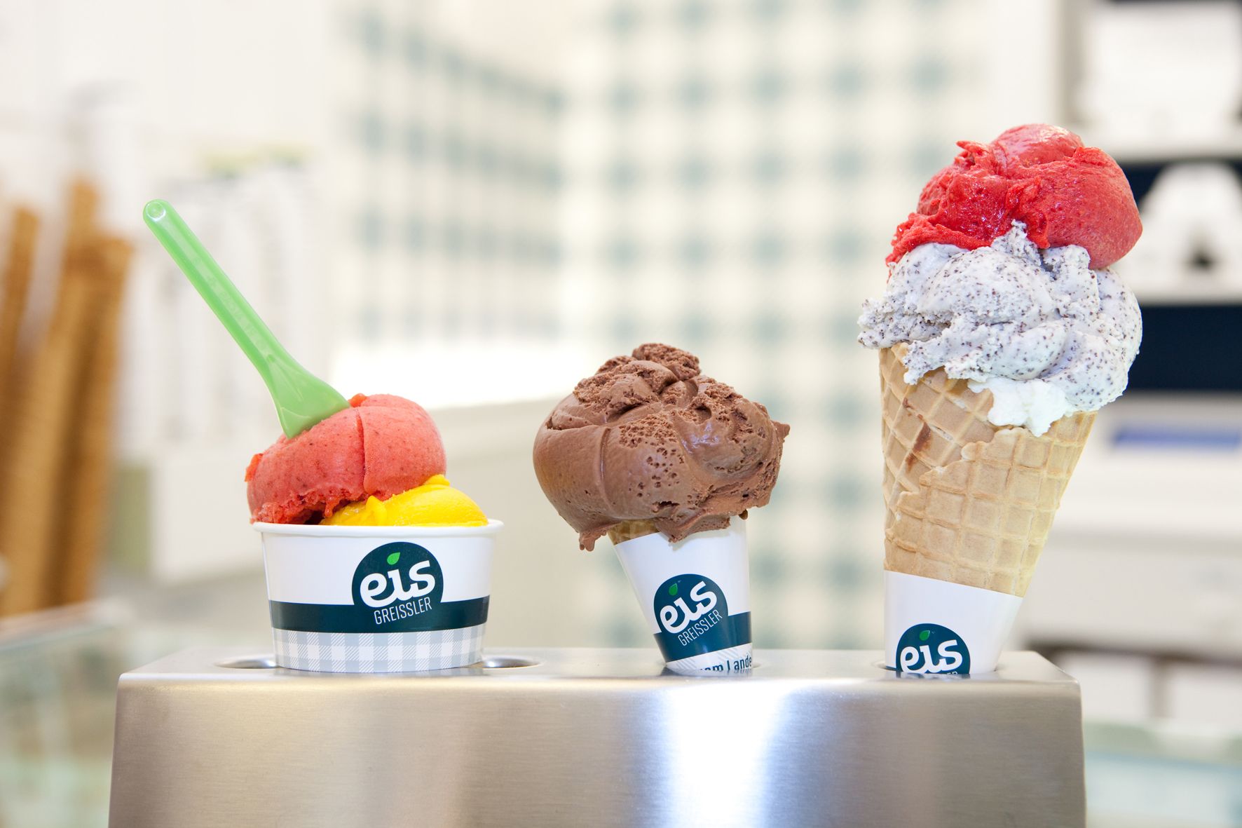 Three ice cream flavors from Eis Greissler in cups and cones.
