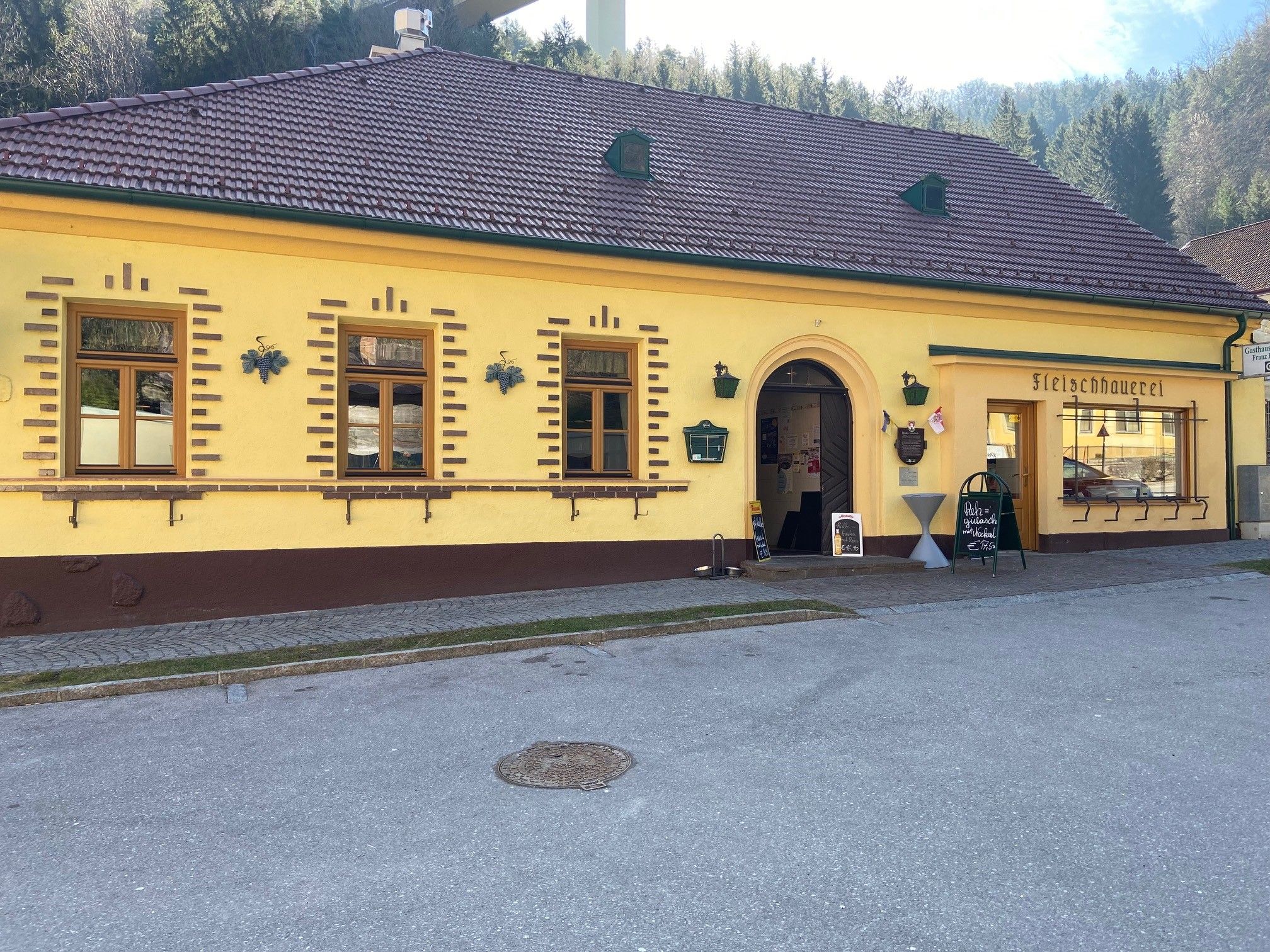 Yellow building with the inscription 'Fleischhauerei' and an entrance.