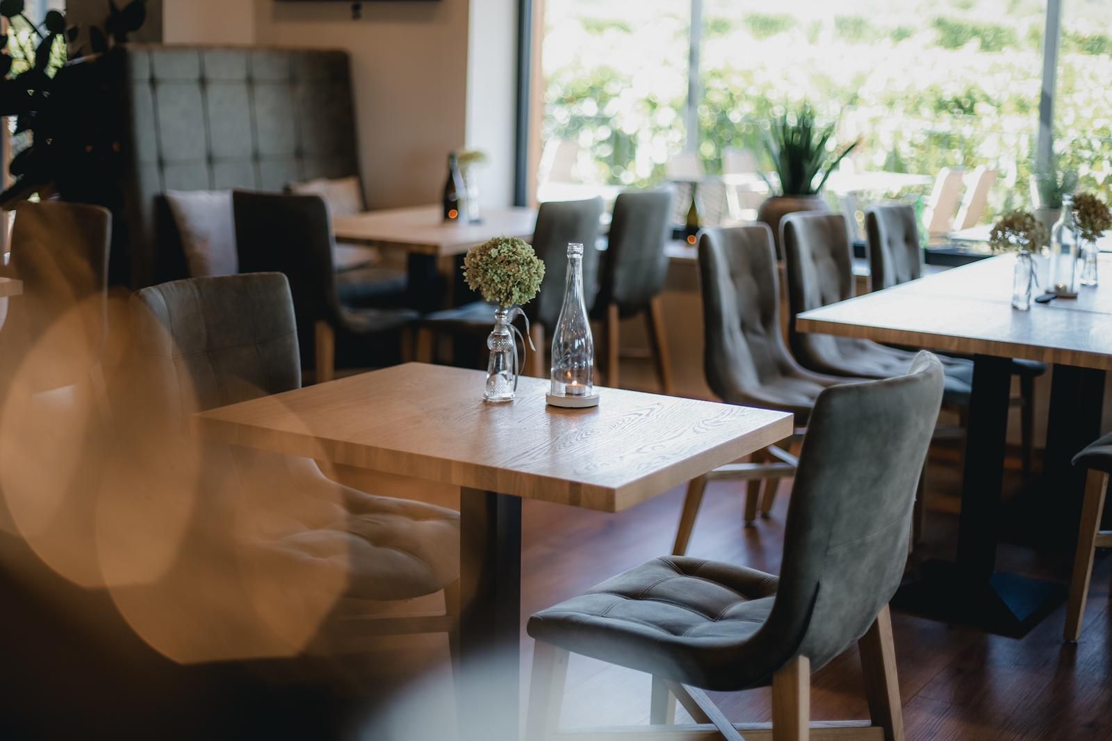 Interior view of a modern wine terrace with wooden tables and upholstered chairs.