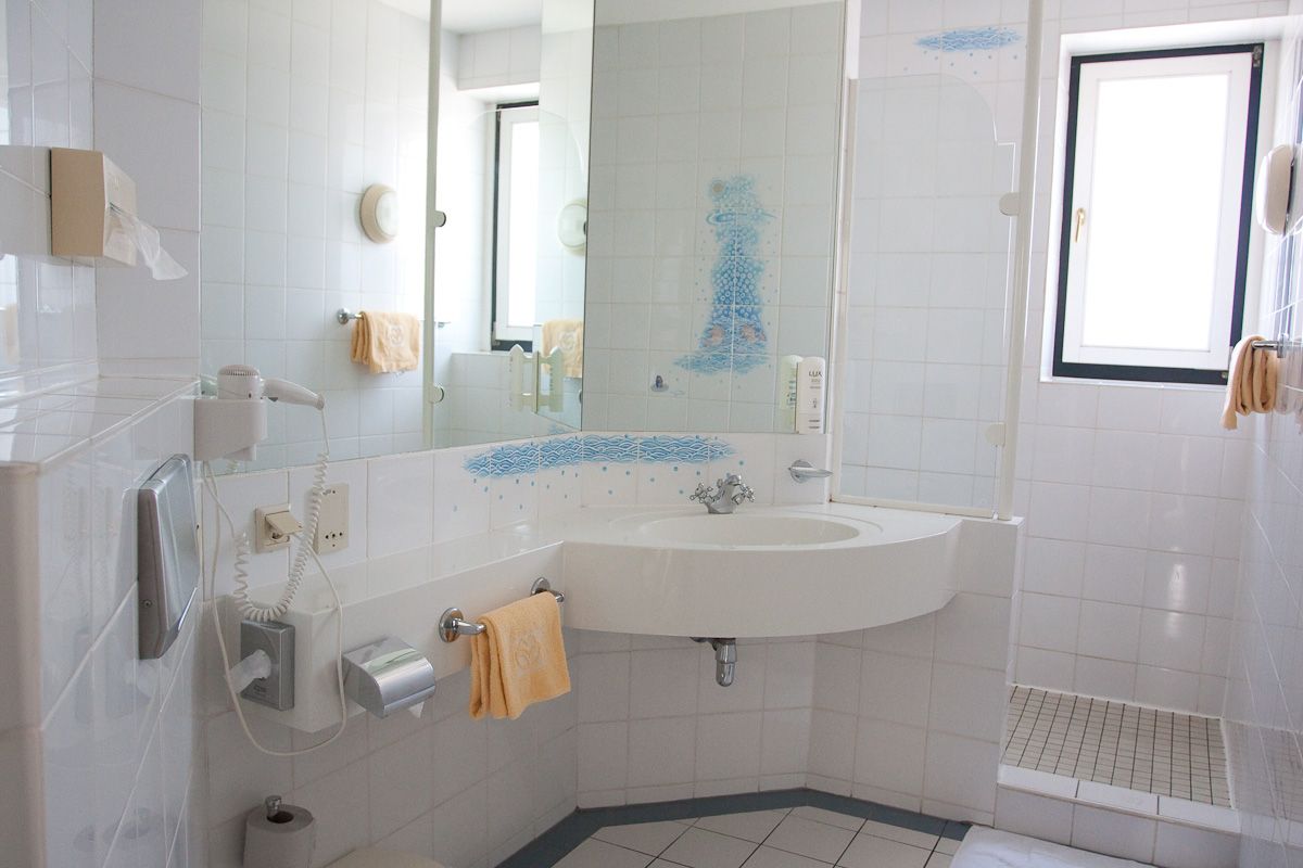 Bright bathroom with washbasin, mirror, shower and towels.