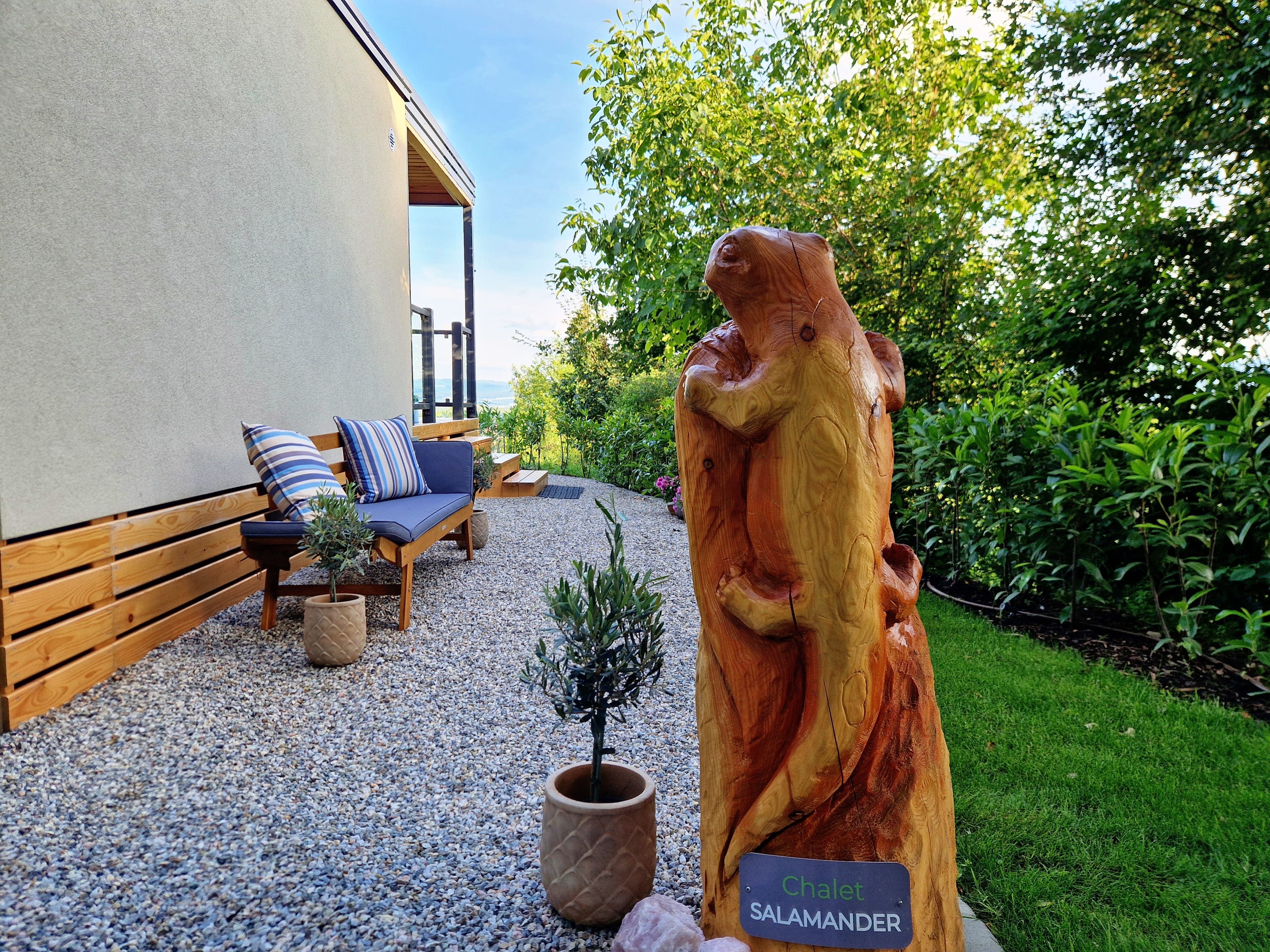 Garden area with wooden sculpture and bench at Chalet Salamander.