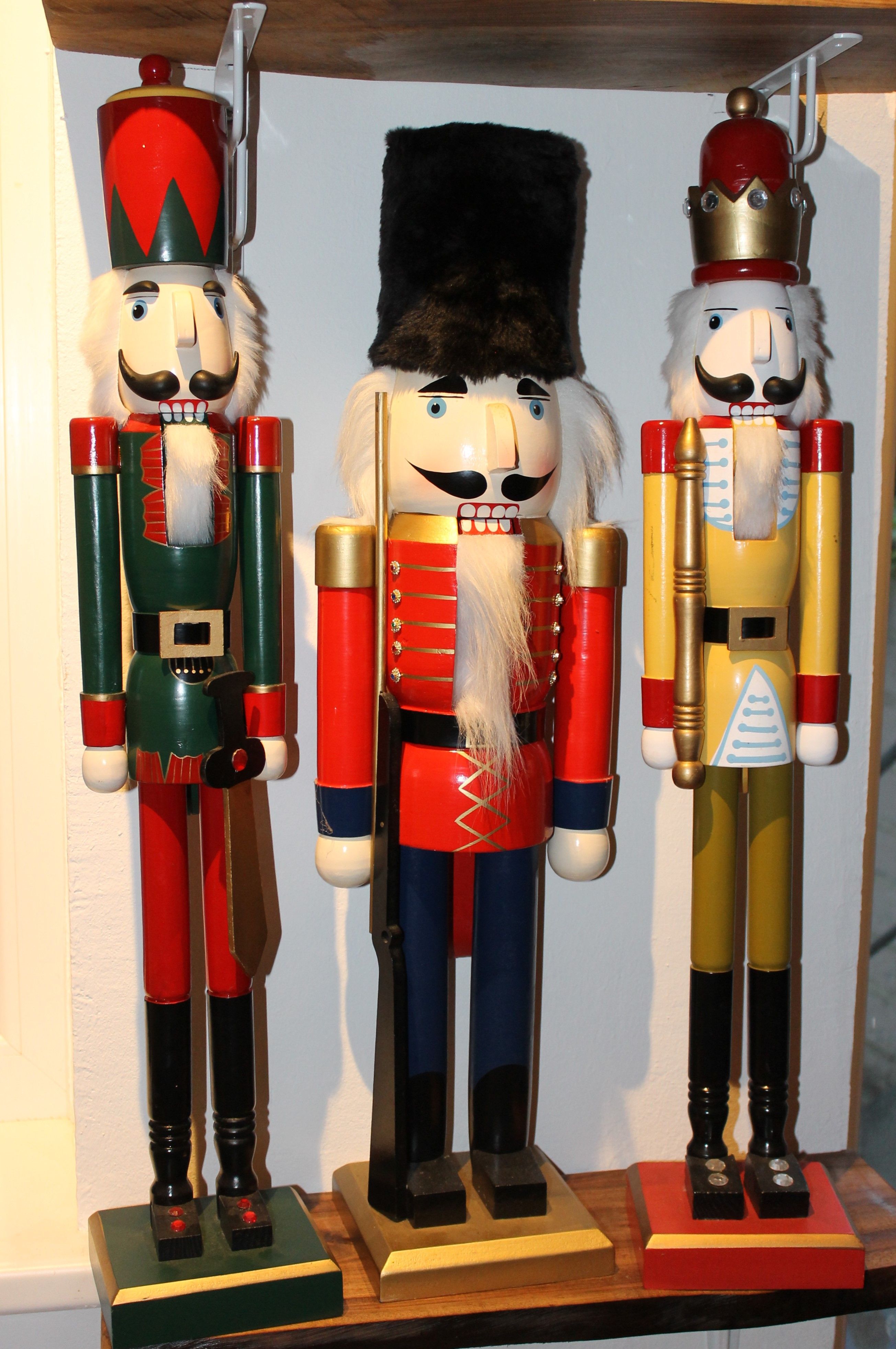 Three colorful nutcrackers in uniforms on a shelf.