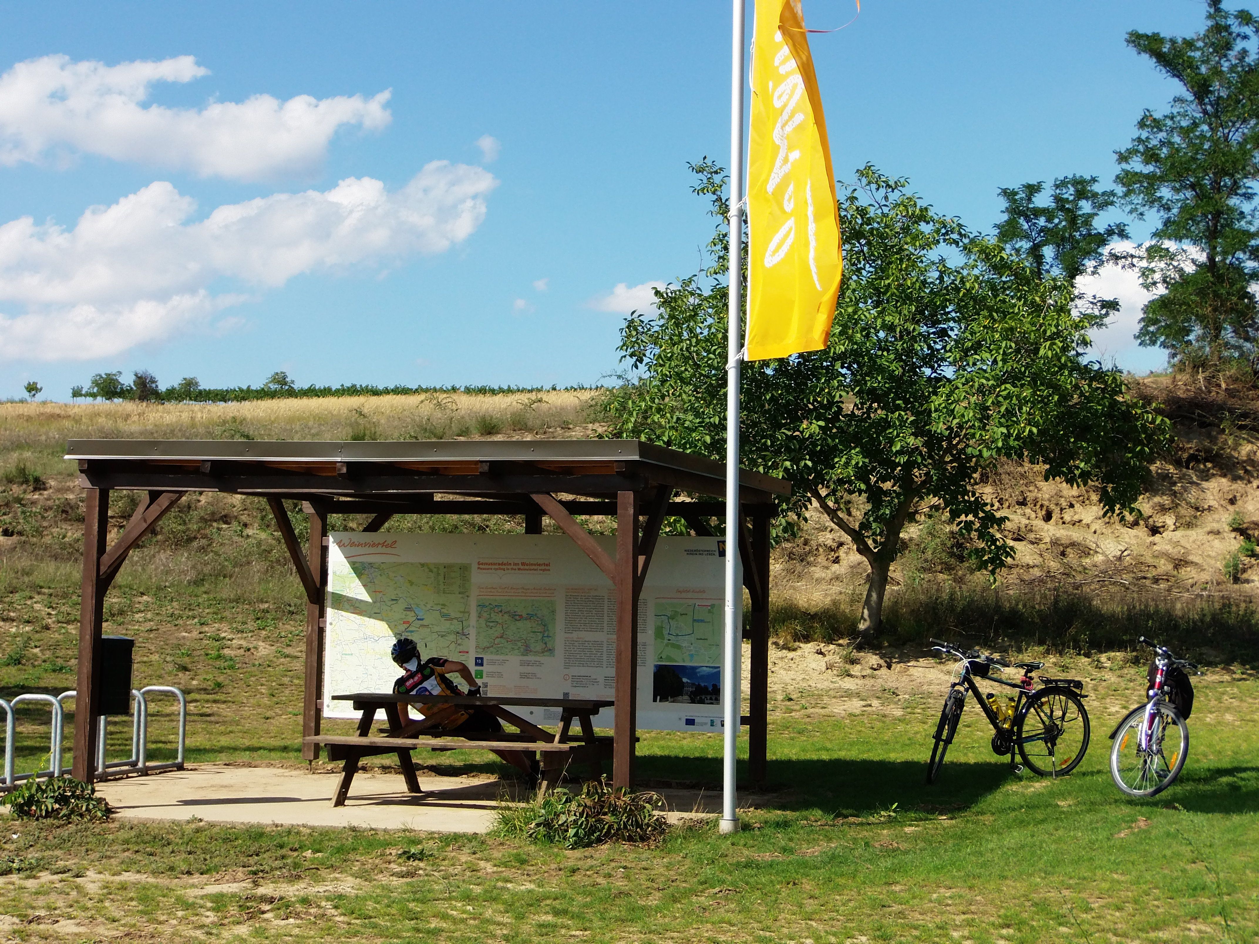 Cyclists' rest area with wooden table, two bicycles and information board in the Weinviertel.