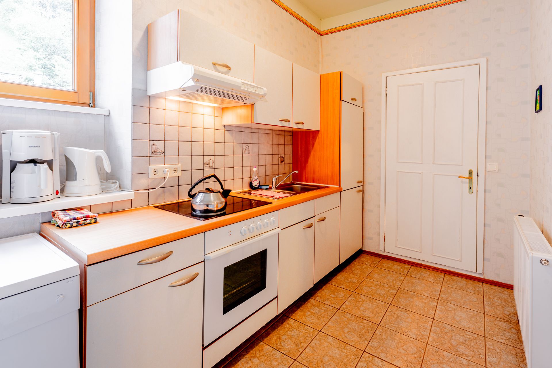 Bright kitchen with stove, sink and coffee machine.