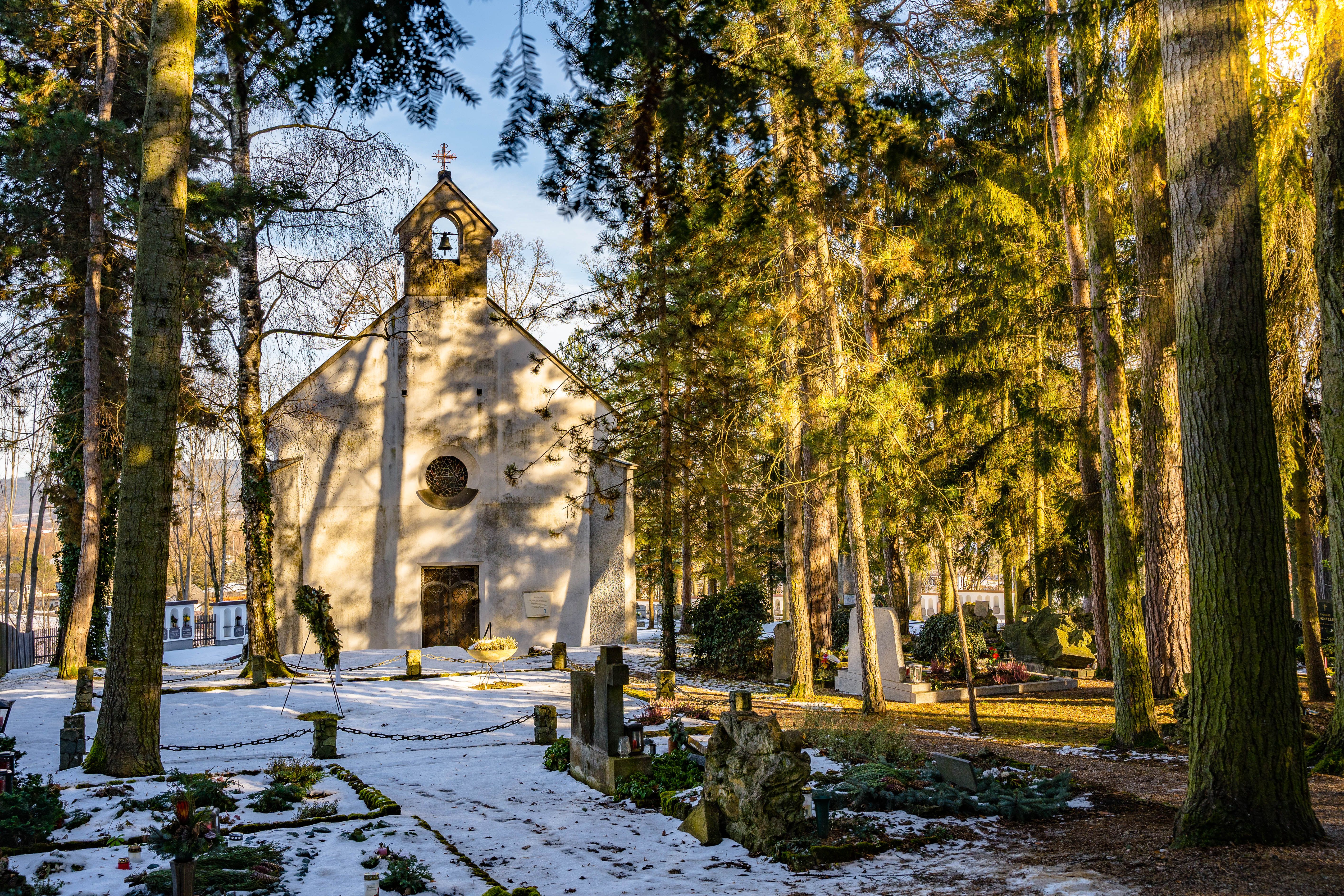 Winter chapel in the forest with snow-covered ground and graves.