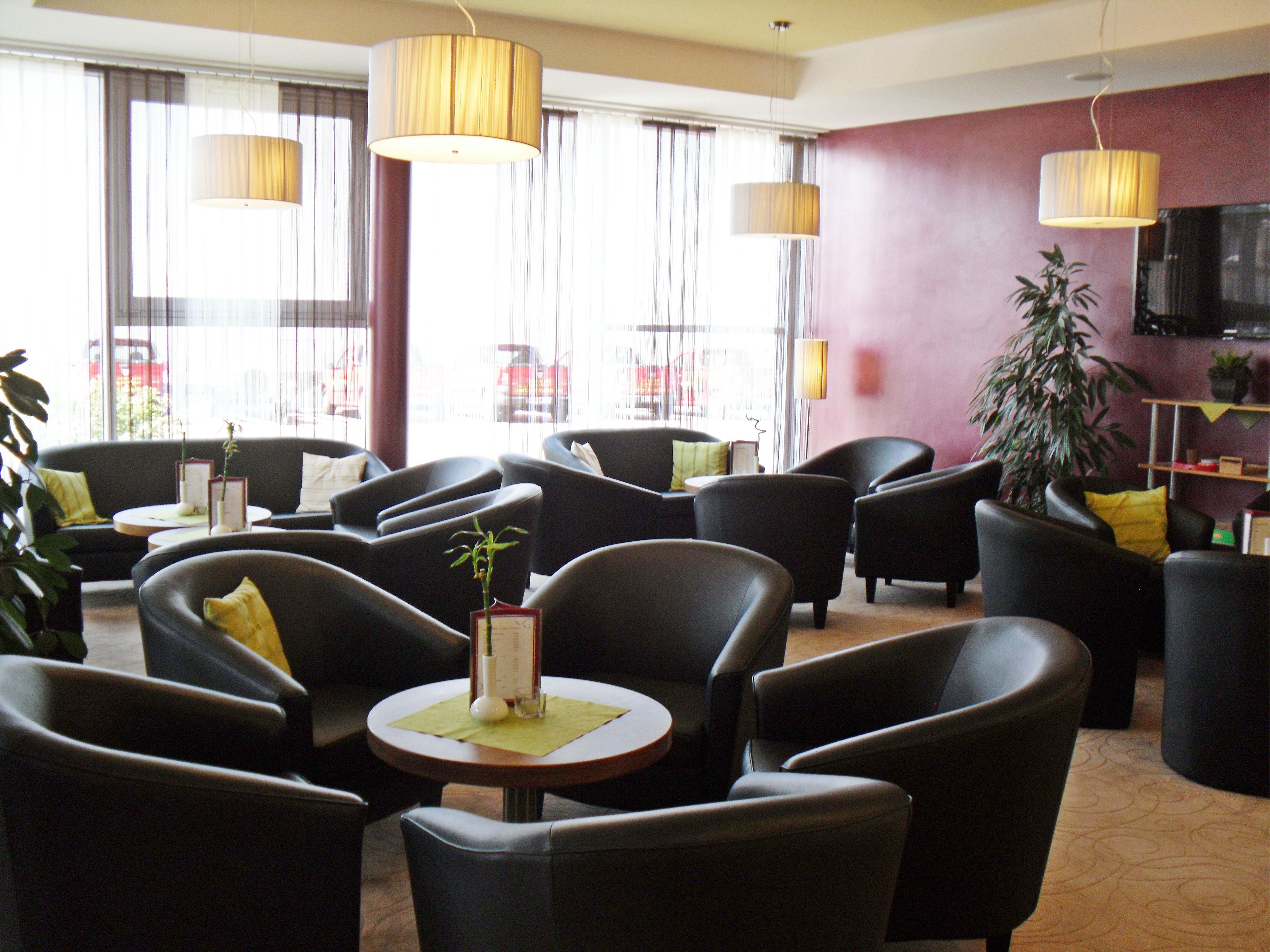Modern lounge with black armchairs, round tables and large windows.