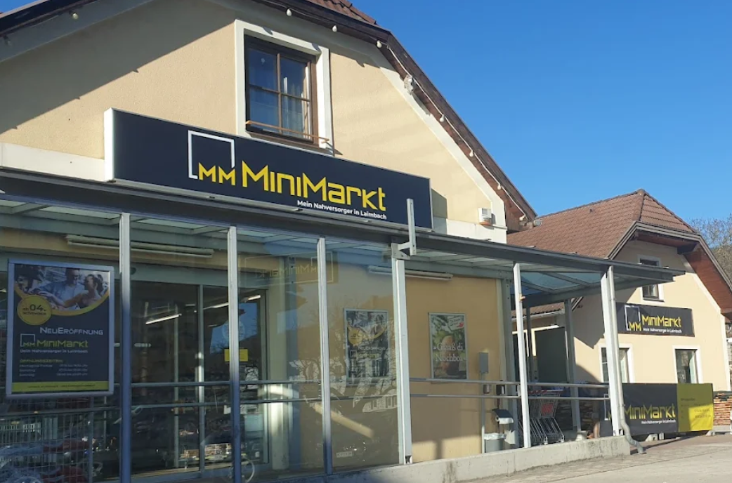 Exterior view of a MiniMarkt store with glass façade and advertising posters.