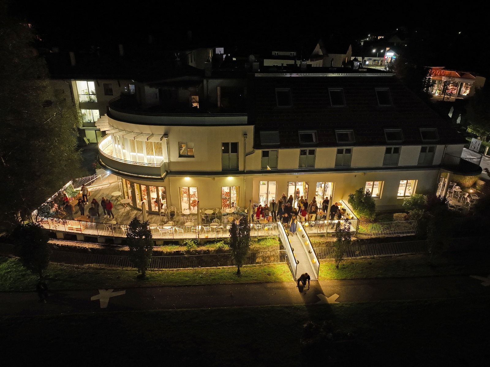 Night shot of the illuminated café with people on the terrace.