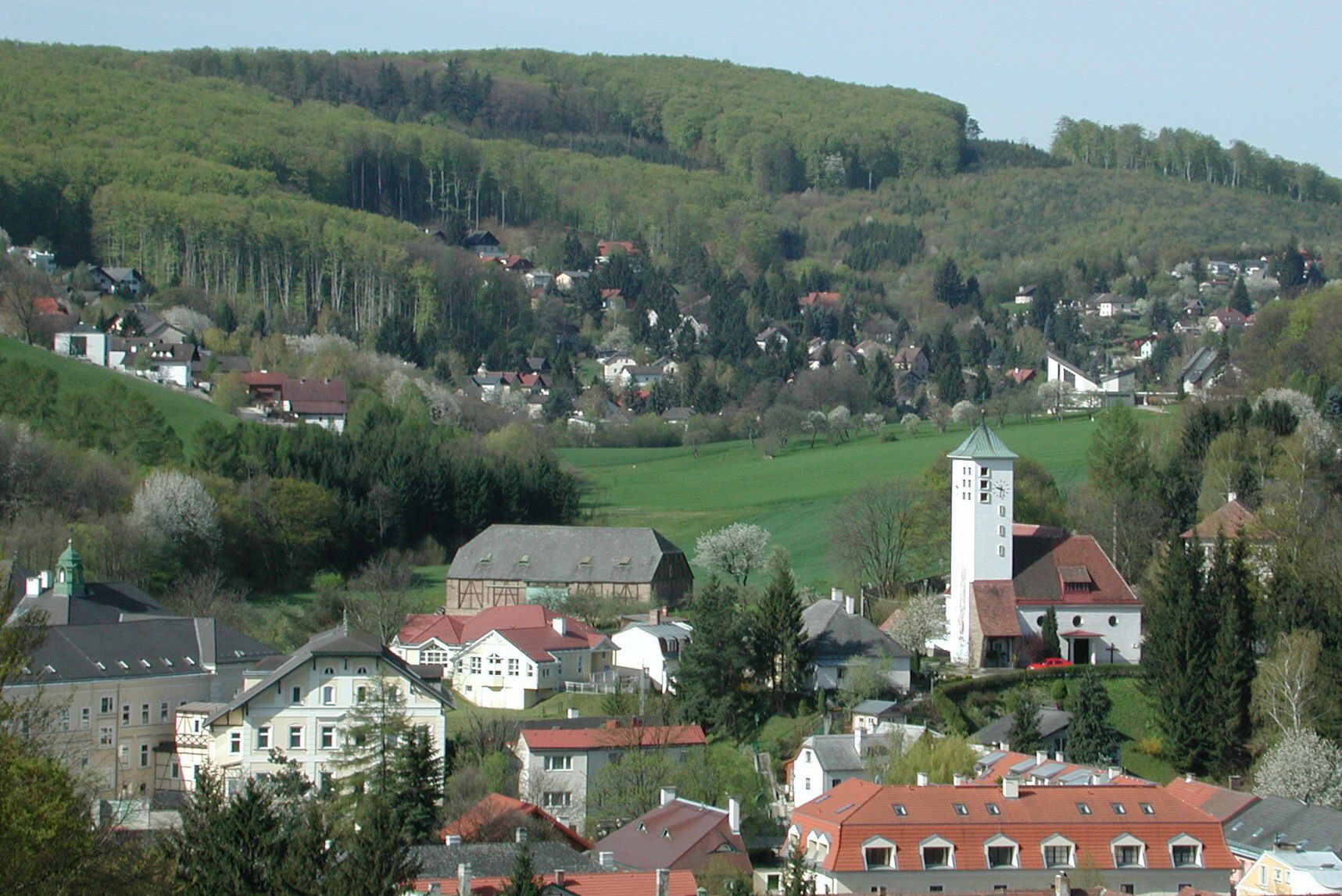 Panorama of Gablitz with church and surrounding houses in front of wooded hills.