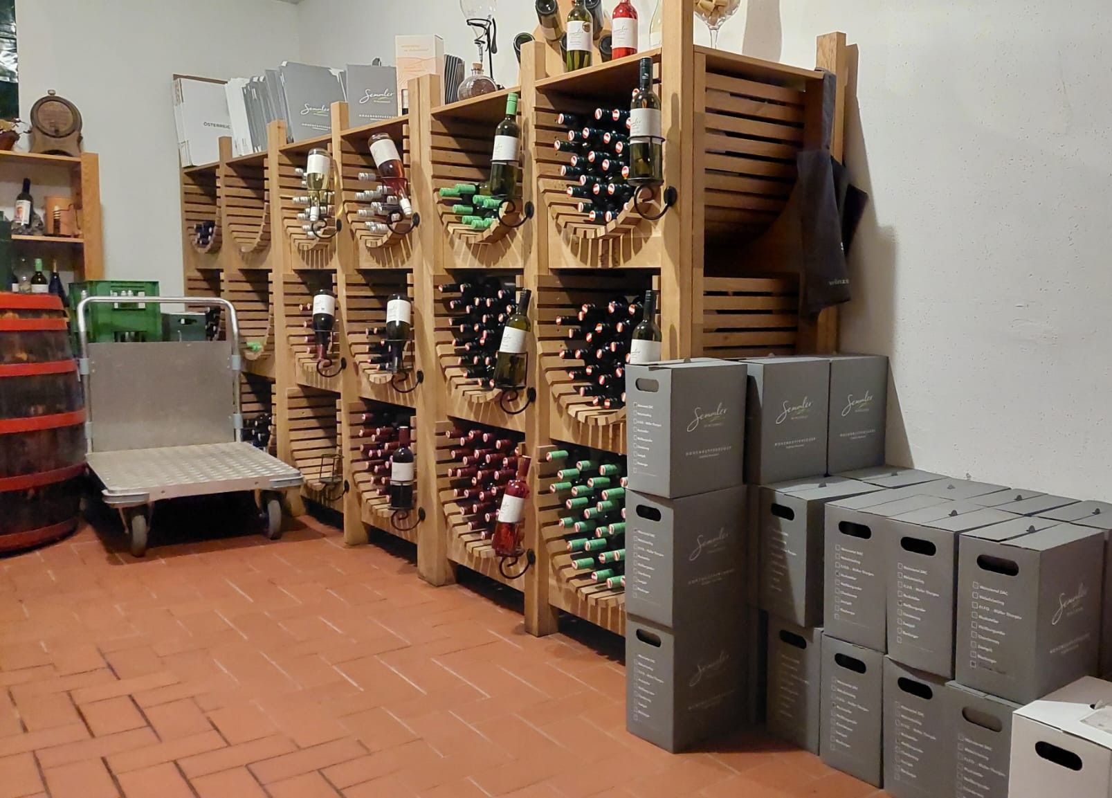 Wine cellar with shelves full of wine bottles and stacked boxes.
