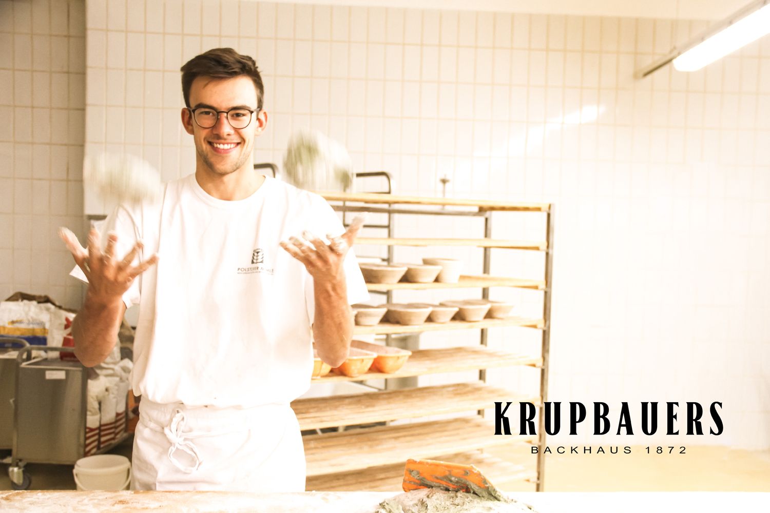 A baker juggles with balls of dough in a bakery.