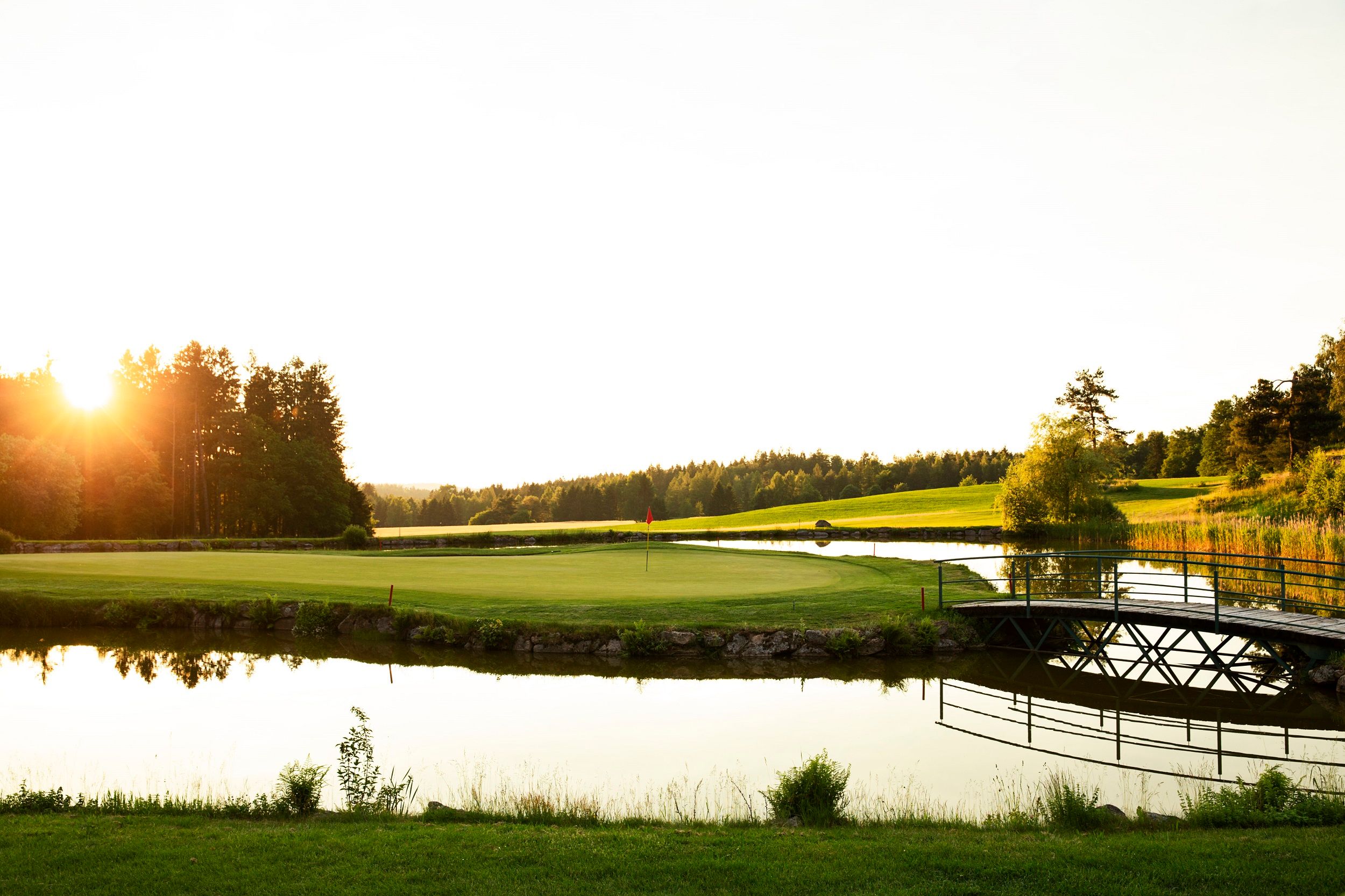 Golf course with pond and bridge at sunset at the Haugschlag golf resort.