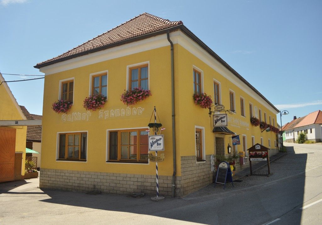 Yellow building with the inscription 'Gasthof Speneder', decorated with flowers.