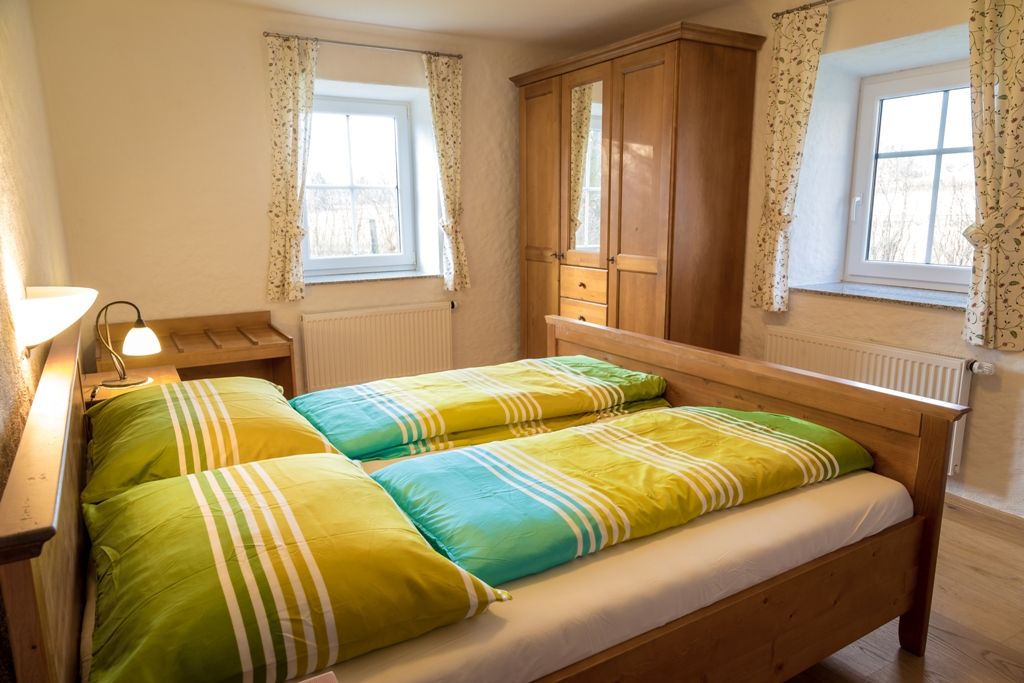 Comfortable bedroom with wooden furniture and colorful bed covers.