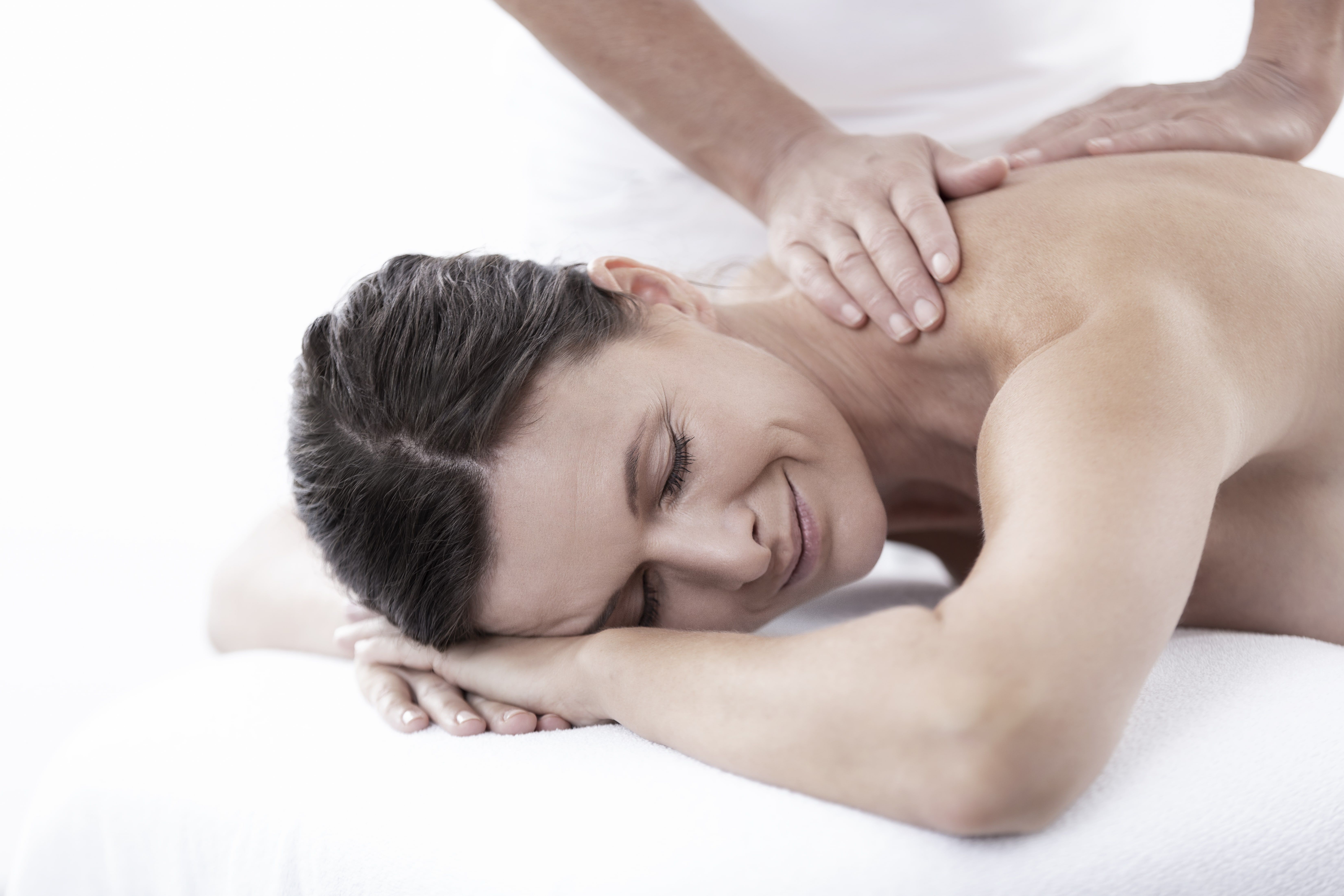 Woman receives a back massage and smiles relaxed.