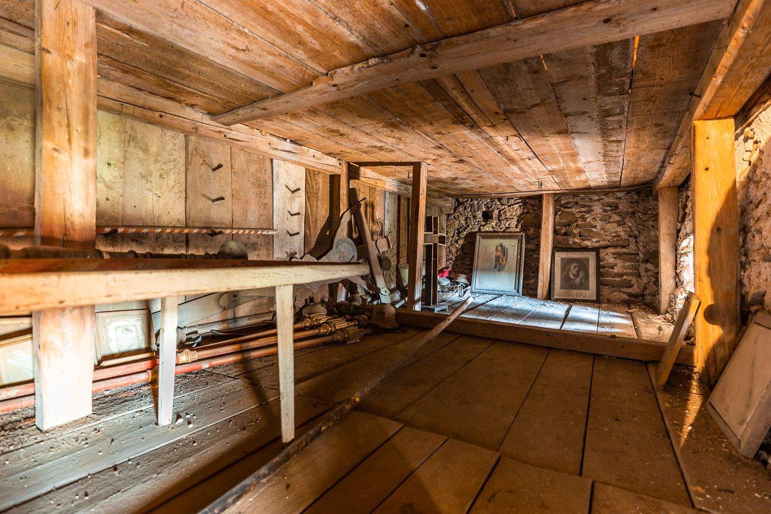 Interior view of the upper floor of the Lichtenegg fortified church with wooden beams and old, dusty pictures.
