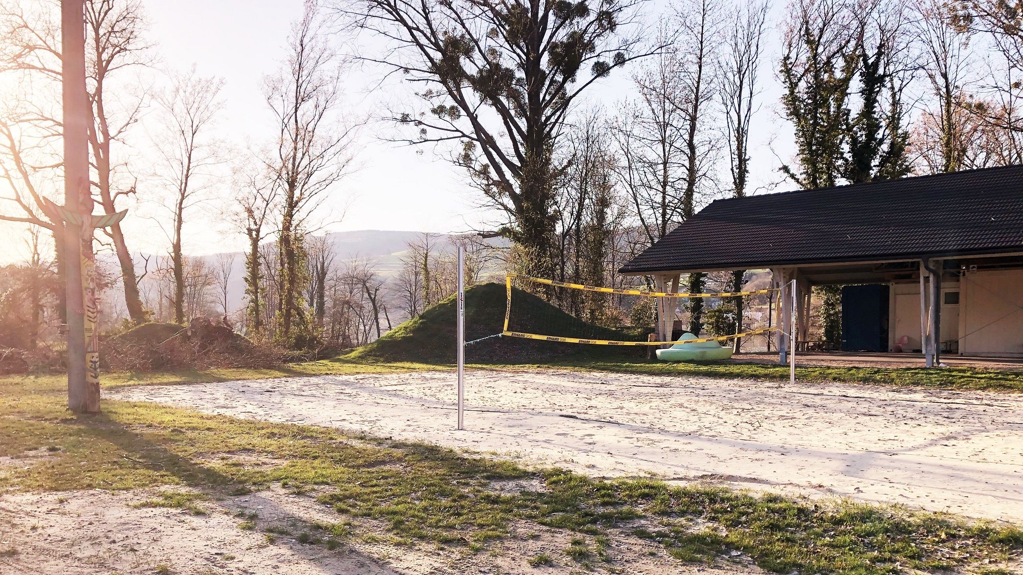 Beach volleyball court in Krummnussbaum with net and trees in the background.