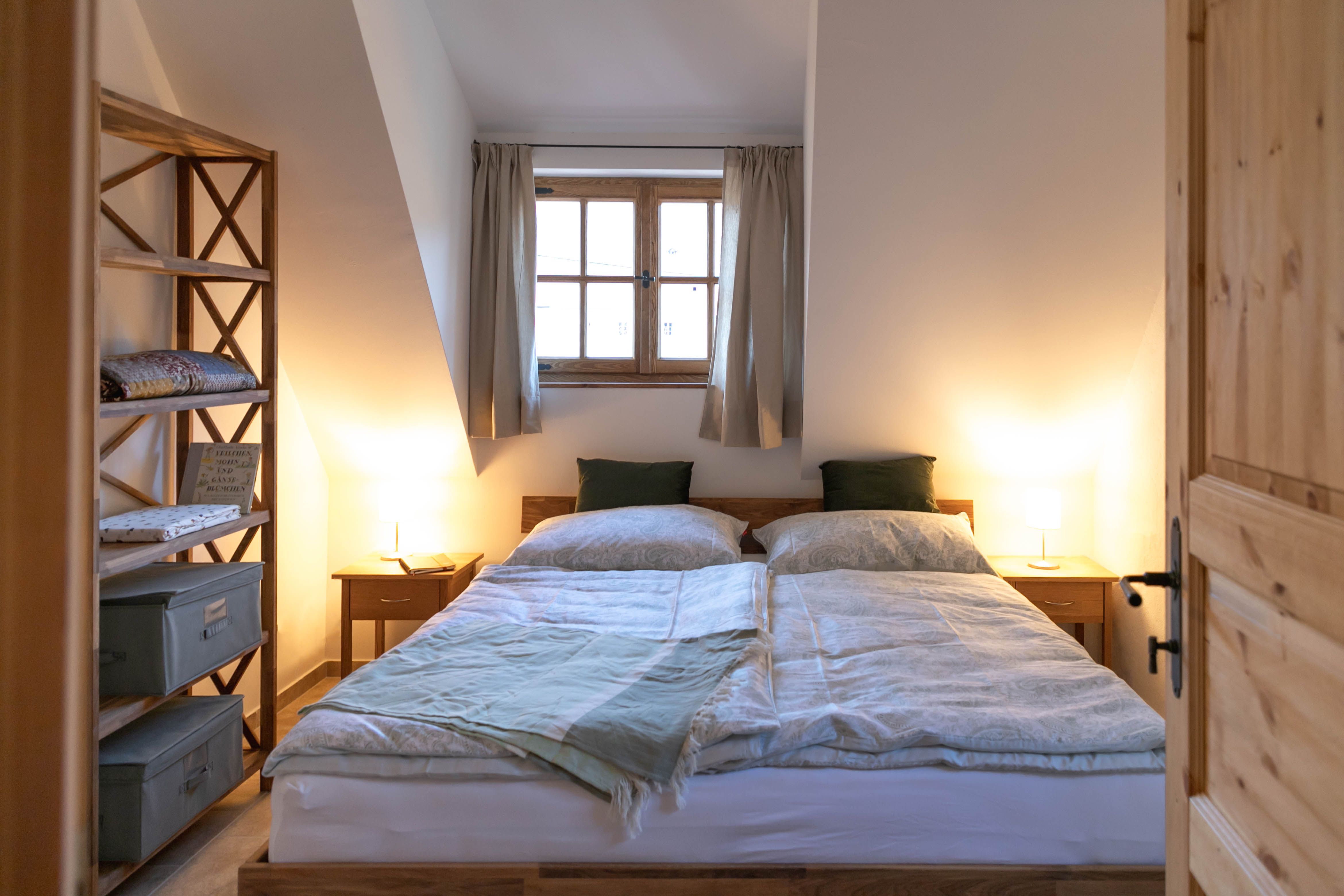 Cozy bedroom with double bed, wooden furniture and window with curtains.