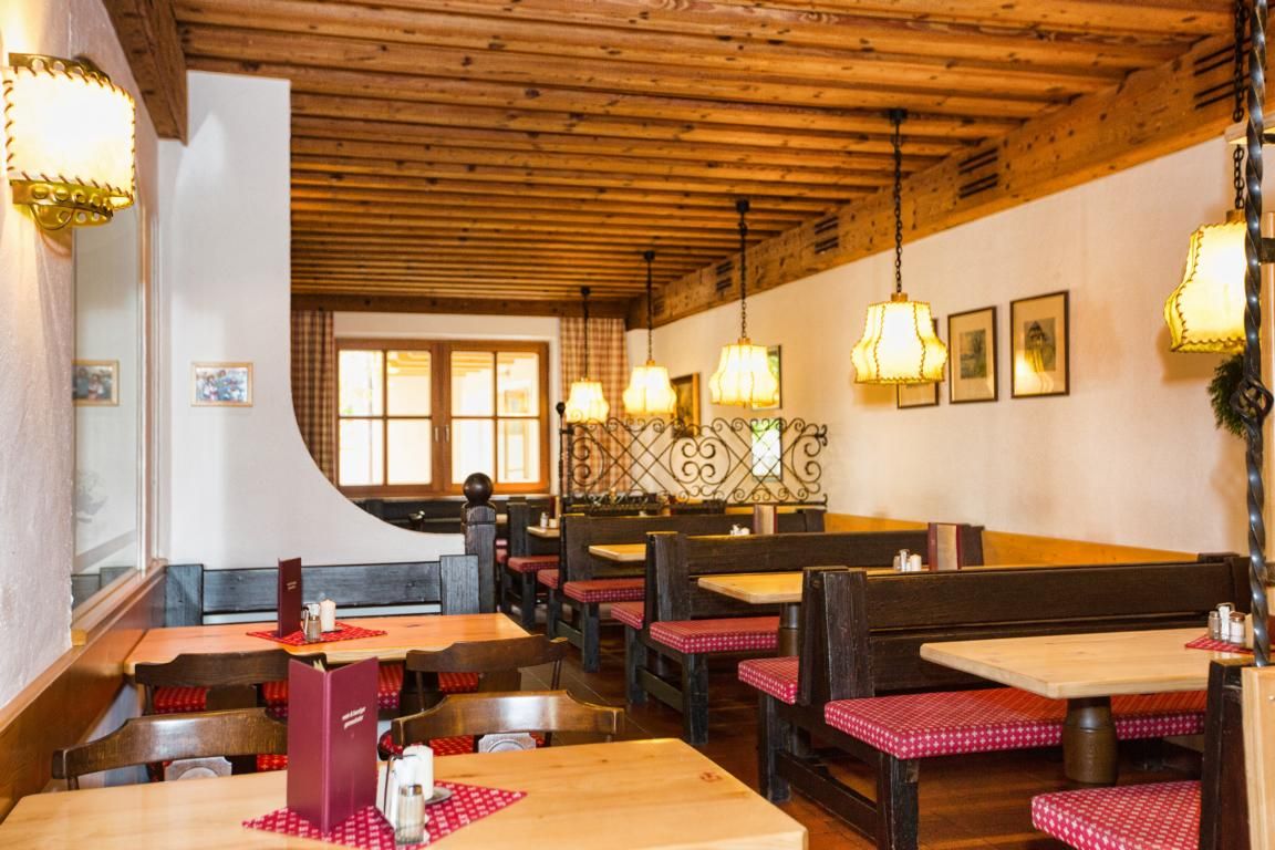 Cozy interior of a traditional wine tavern with wooden furniture and checkered seat cushions.