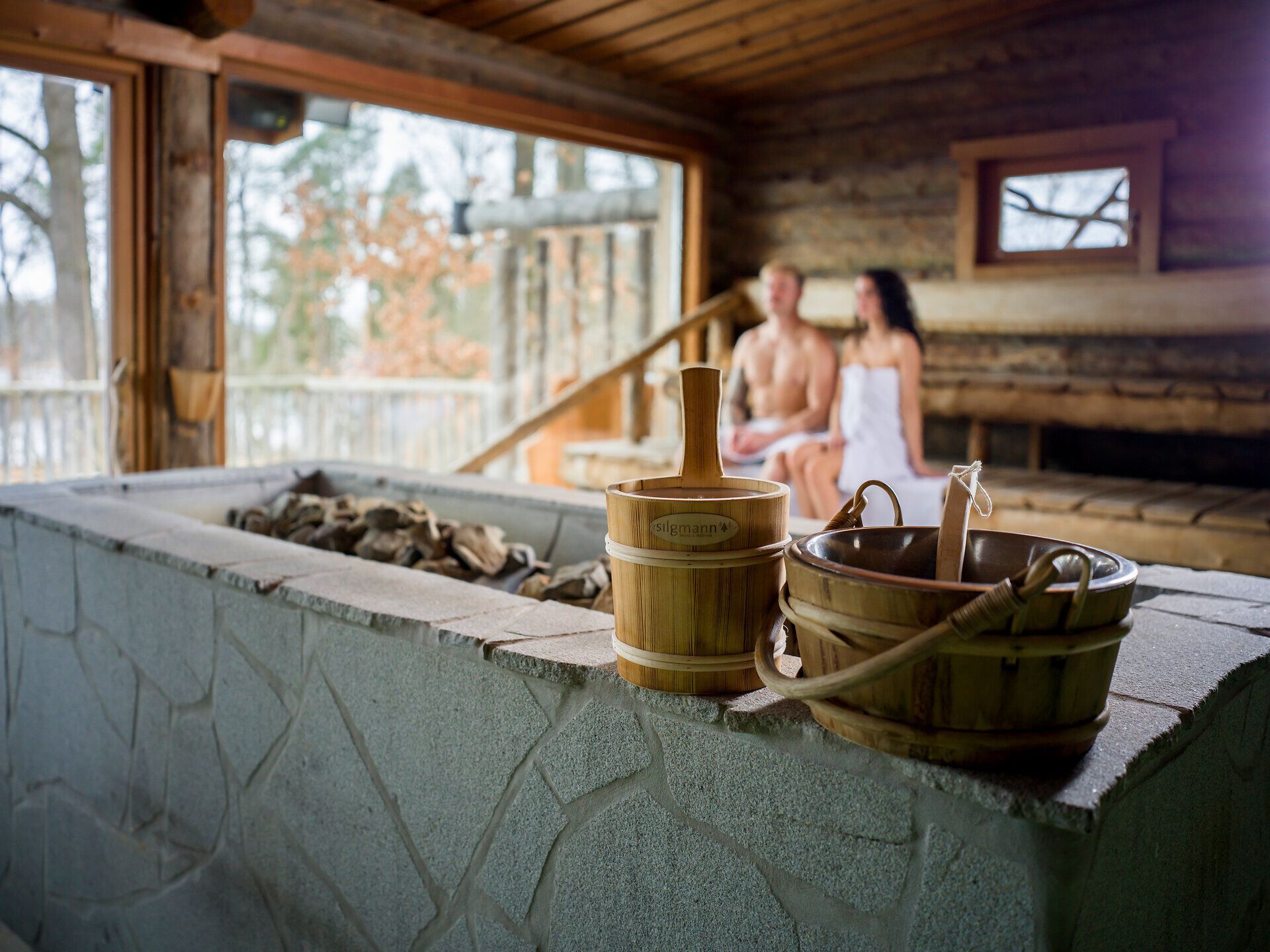Modern hotel room with double bed, nature picture on the wall, armchair, table and floor lamp.