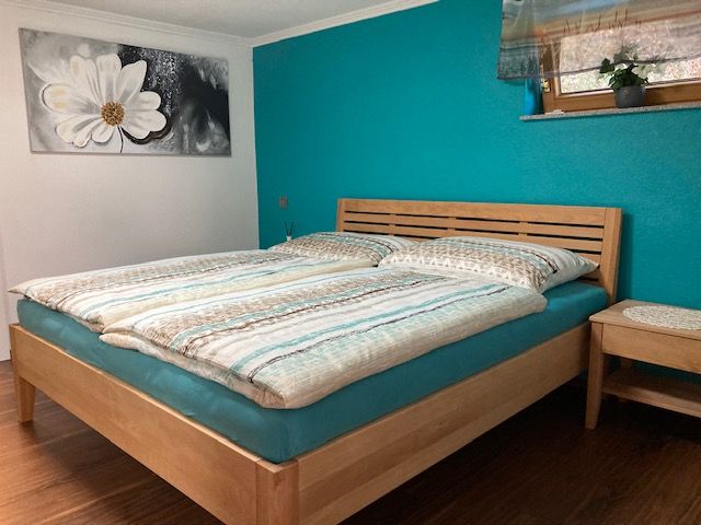 Bedroom with double bed, turquoise wall and flower picture.