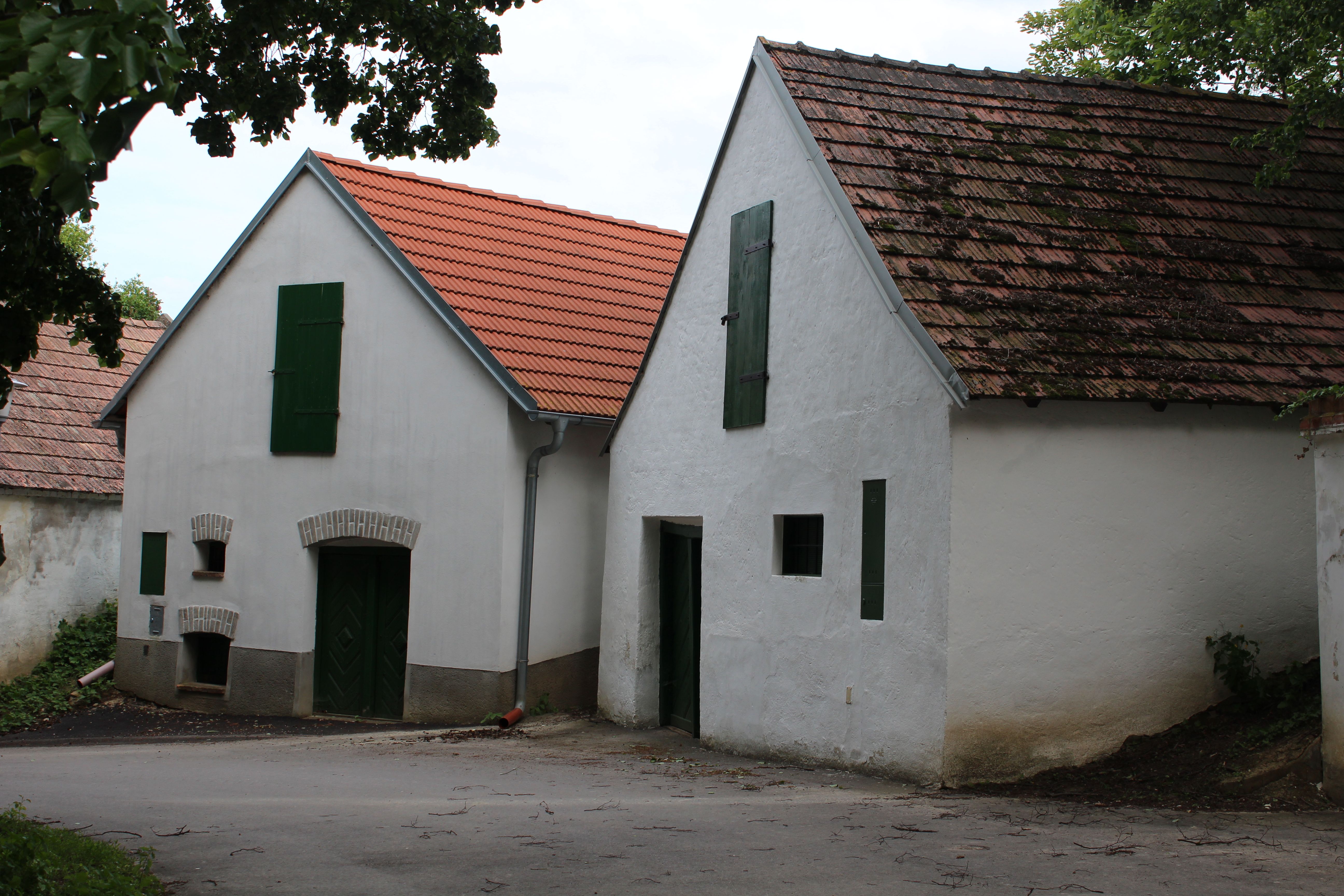 Two traditional wine cellars with white walls and red tiled roofs in a wine cellar lane.