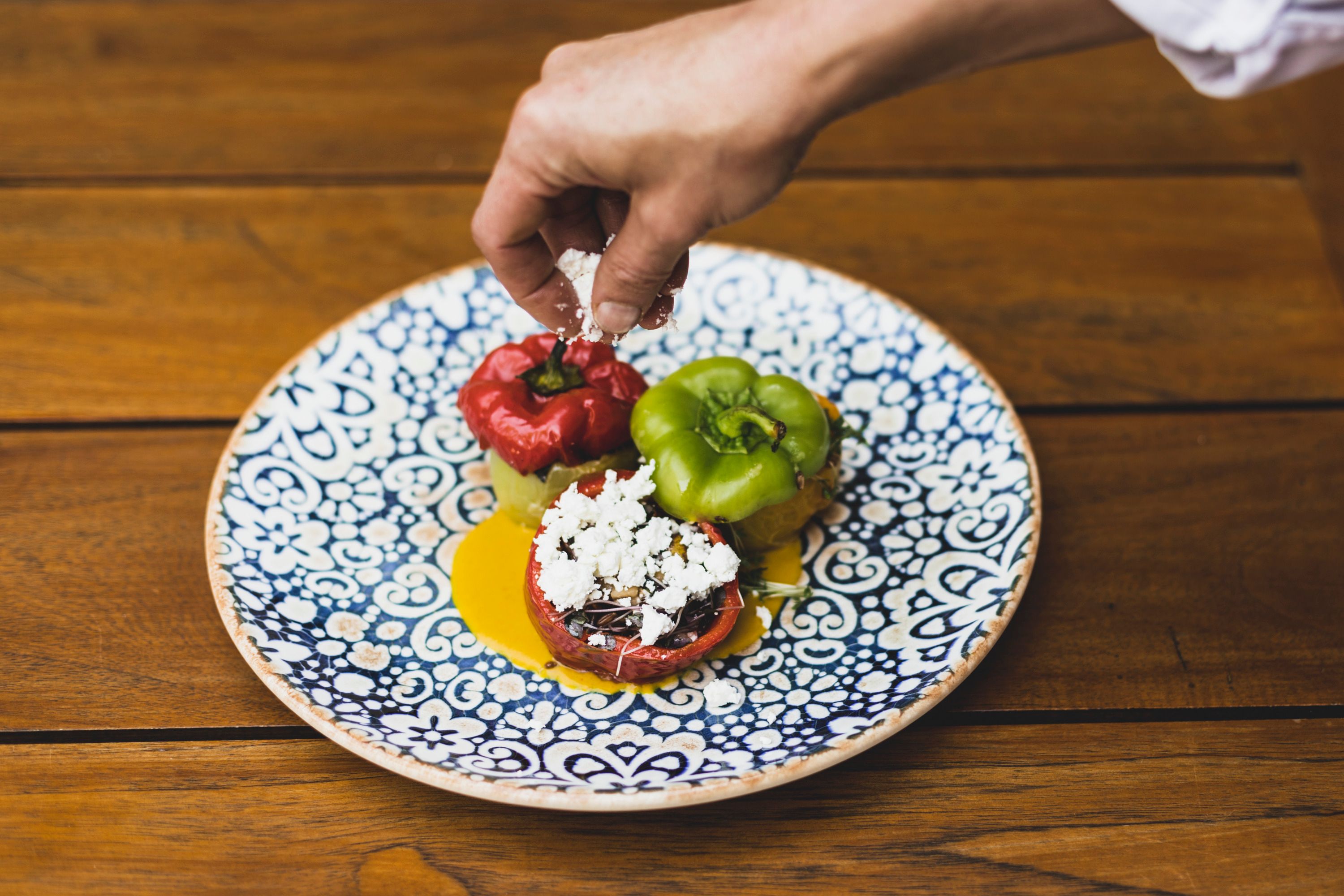 A plate of stuffed peppers, decorated with cheese, on a wooden table.