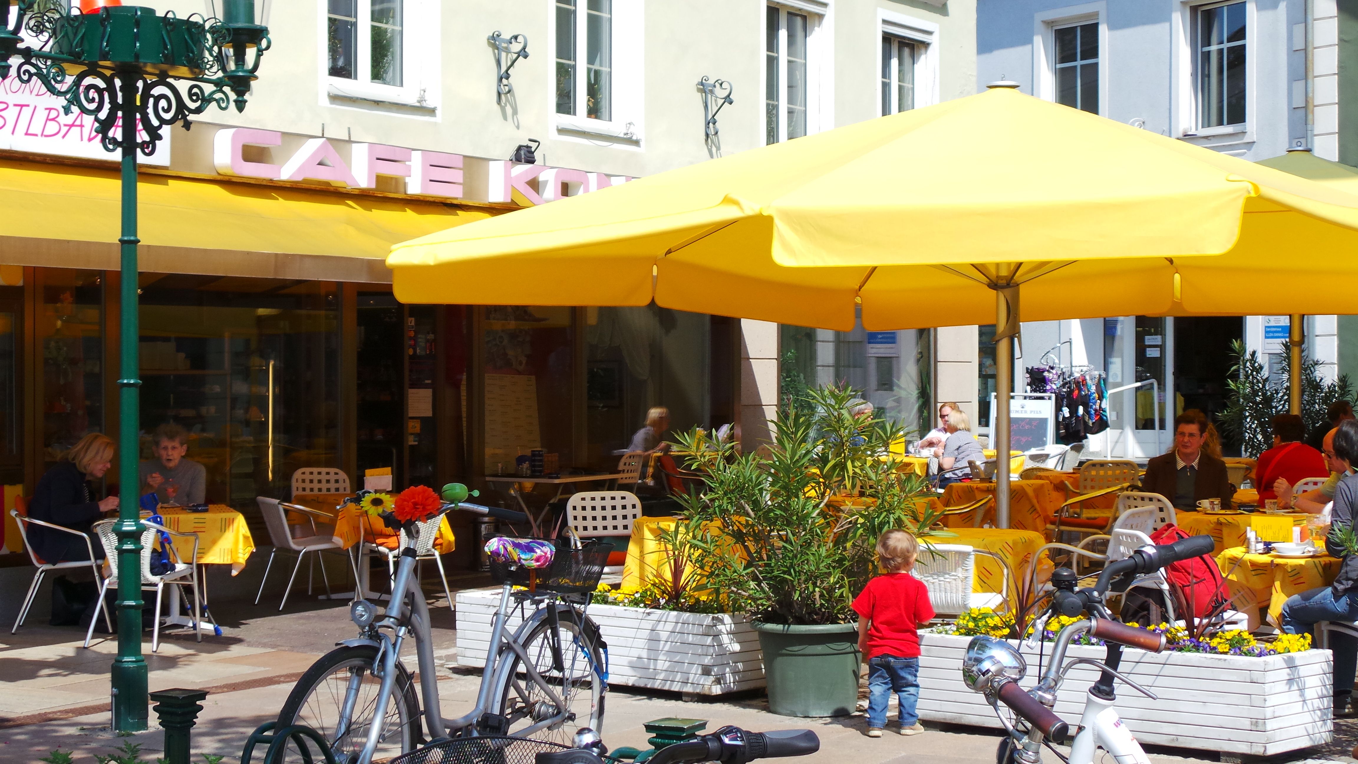 Outdoor area of a café with yellow parasols and guests at tables.